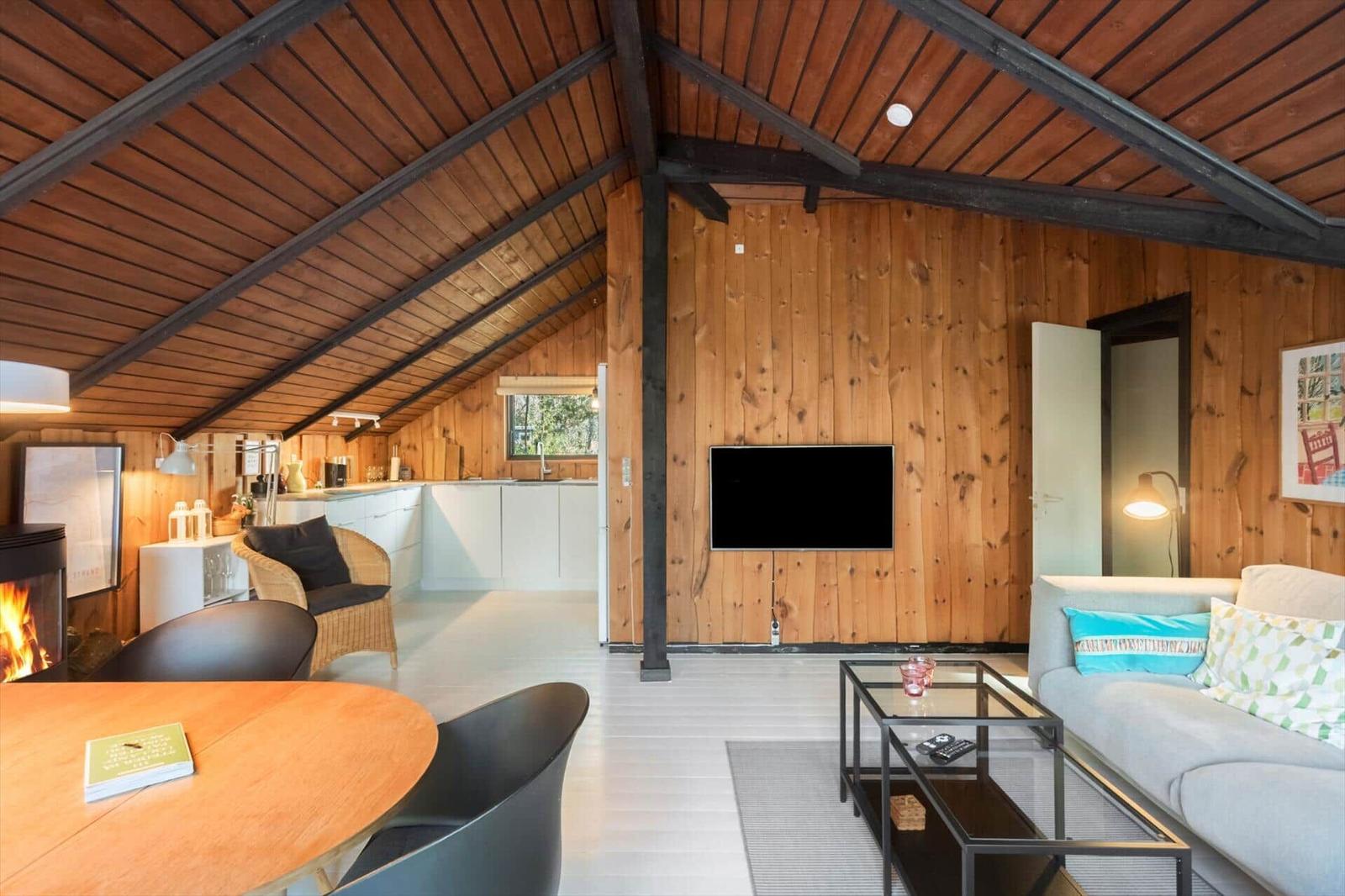 Wohnbereich mit Kamin, TV und Essbereich unter Holzdach