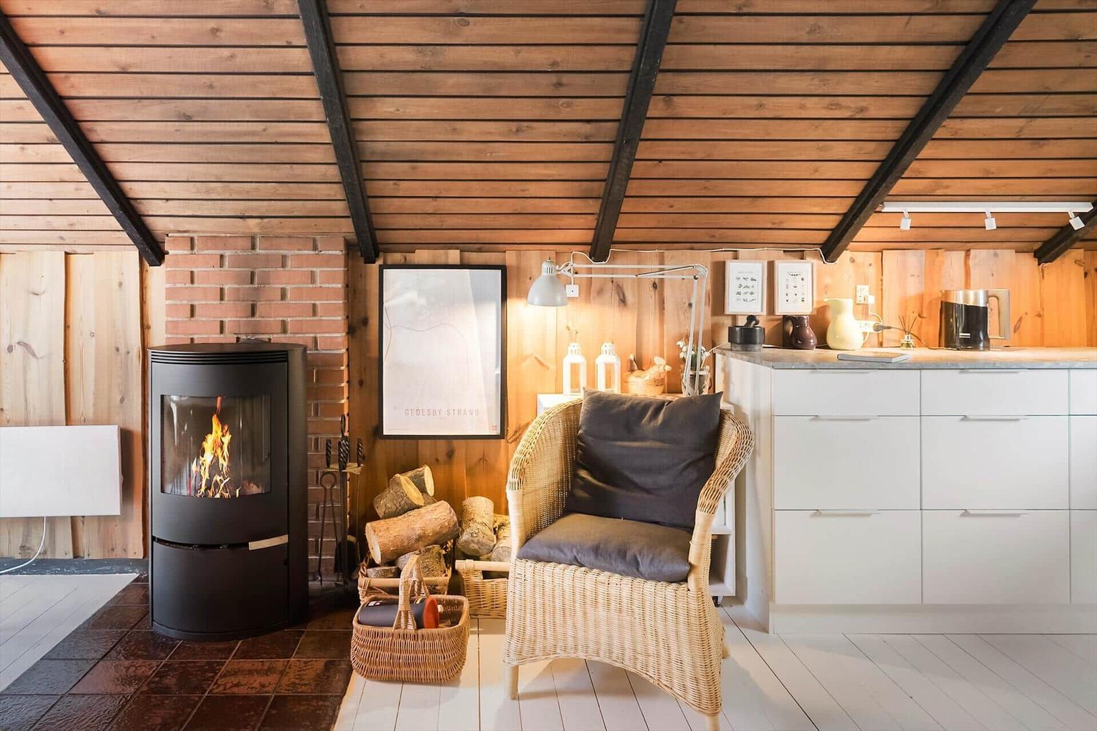 Küche mit weißen Schränken und Kaminofen mit brennendem Holz.