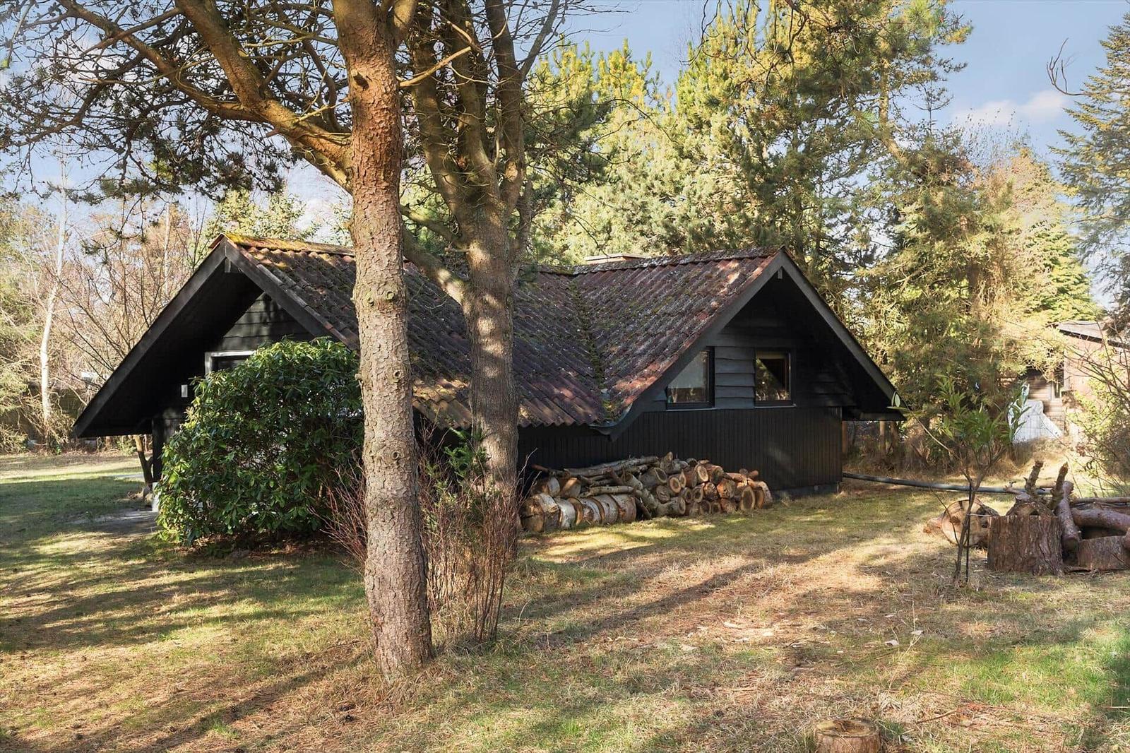 Holzhaus mit Schopfdecke und Holzstapel im Garten