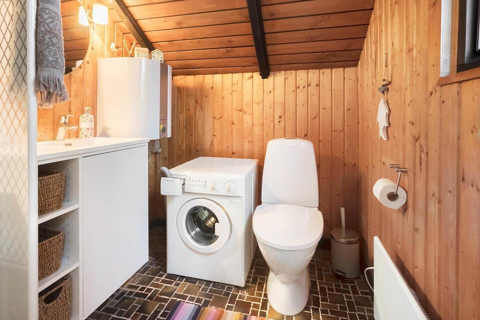 Badezimmer mit Waschmaschine, Toilette und Waschbecken.