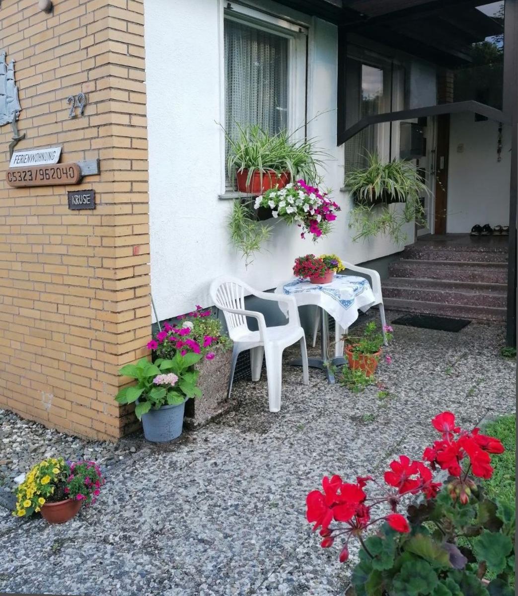 Vor dem Haus steht ein Tisch mit zwei Stühlen. Blumen und Pflanzen schmücken die Terrasse.