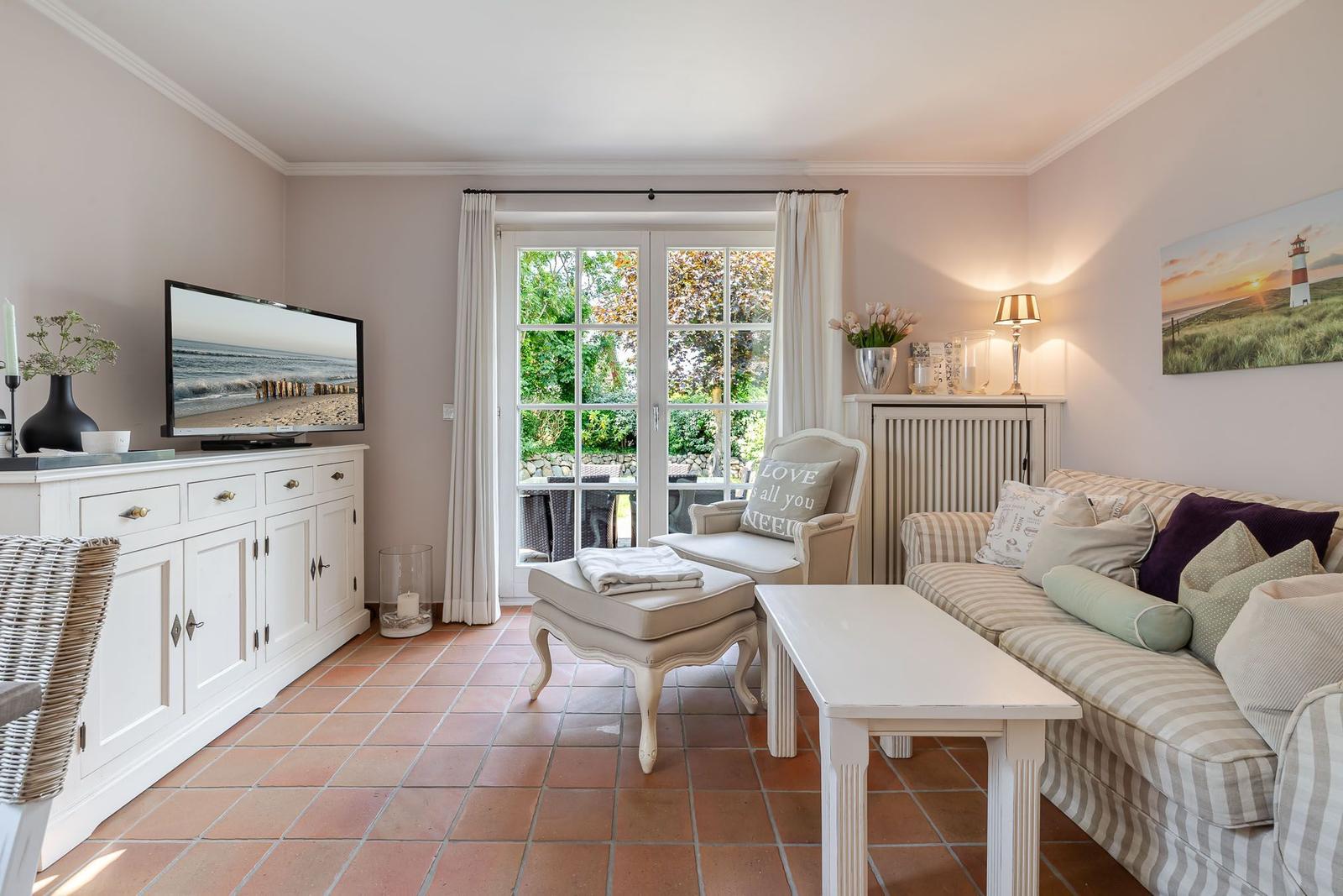 Wohnzimmer mit Sofa, Fernseher und Terrassentür.