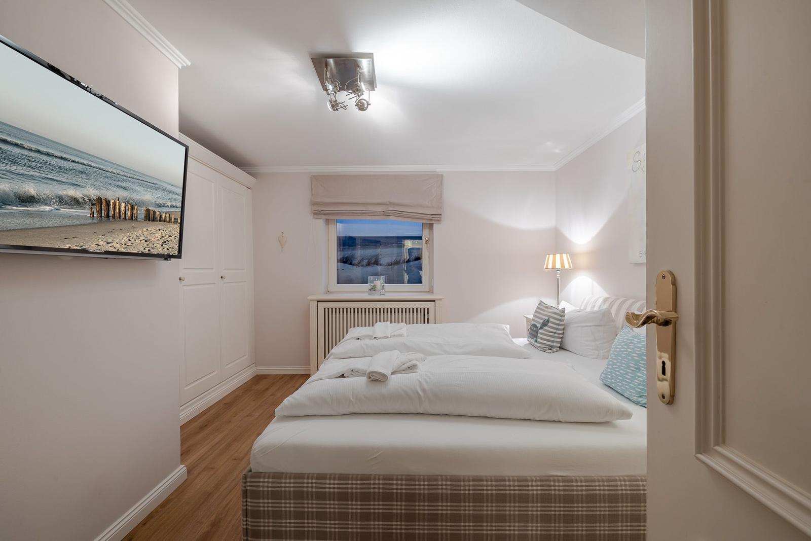 Schlafzimmer mit Doppelbett, TV und Fenster mit Blick aufs Meer.