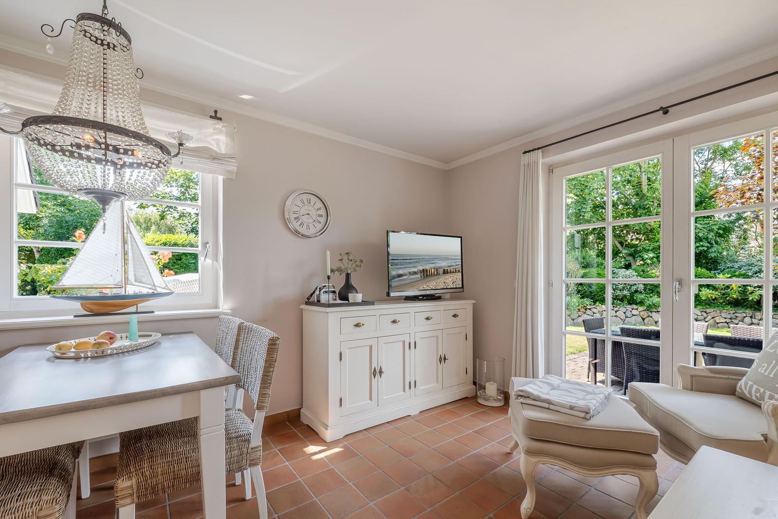 Essbereich mit Tisch, Stühlen und Fenster. Fernseher auf Schrank. Terrasse mit Sitzgelegenheit.