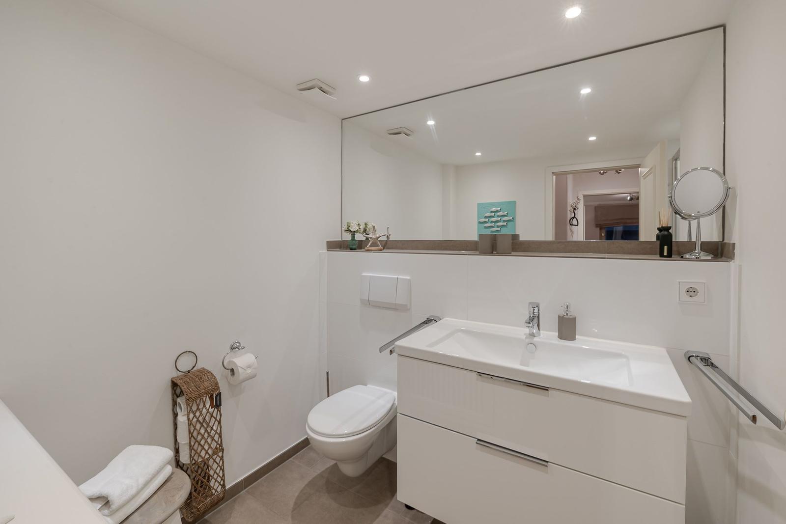 Badezimmer mit Waschbecken, Spiegel und Toilette. Modern eingerichtet.