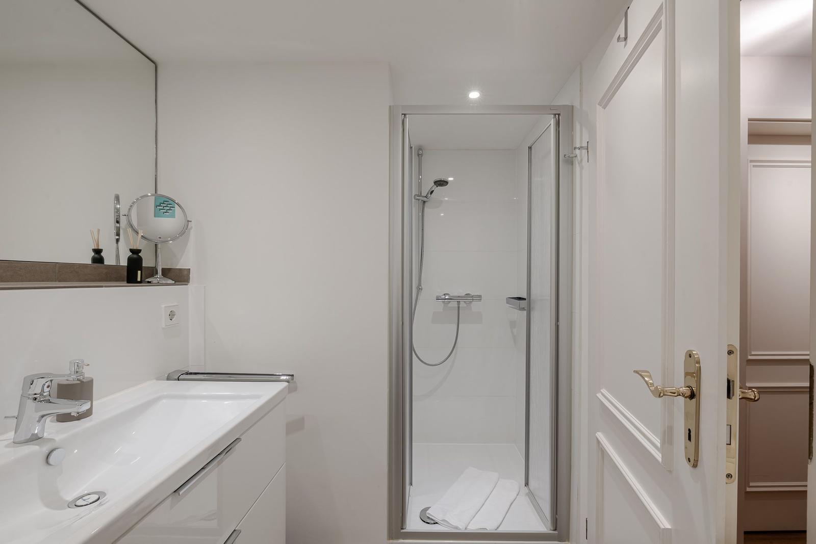 Badezimmer mit Dusche, Waschbecken und Spiegel