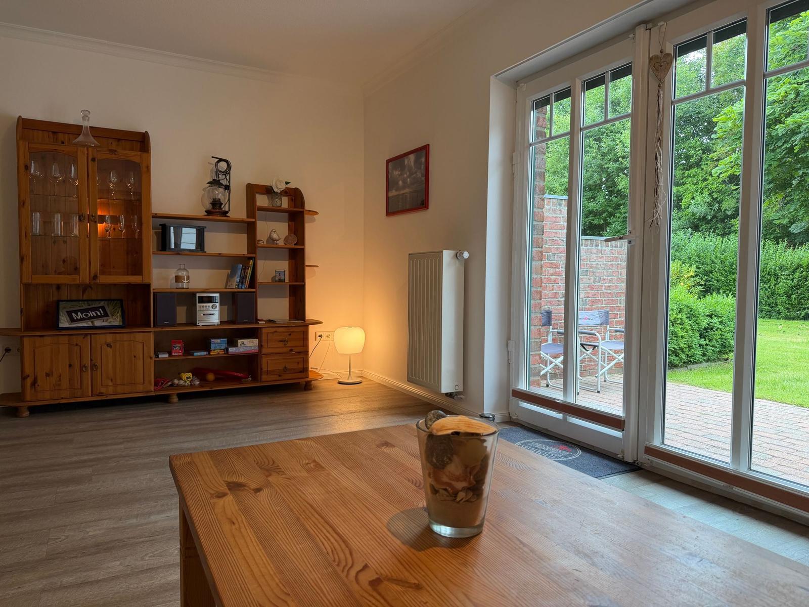 Ein Raum mit Holzmöbeln, Glasfront und Blick auf einen Garten.
