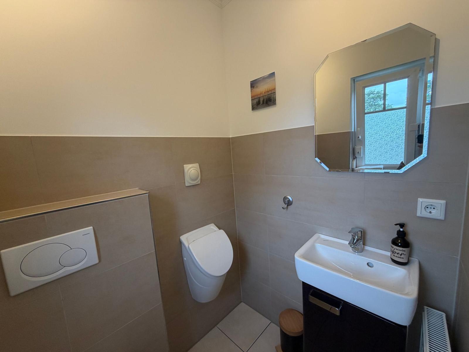 Badezimmer mit Toilette, Waschbecken und Spiegel
