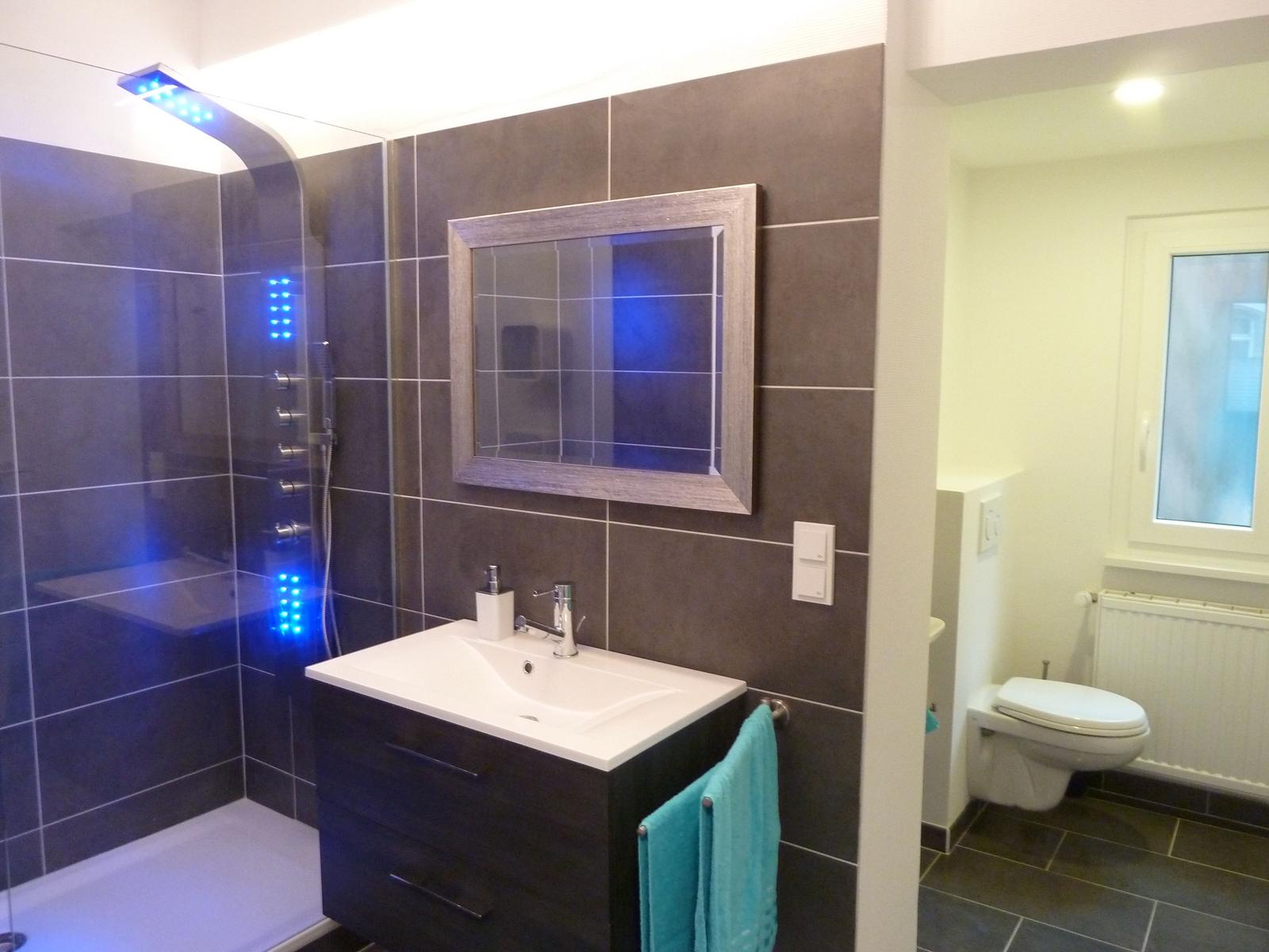 Bad mit Dusche, Waschbecken und Toilette. Dusche mit LED-Beleuchtung.