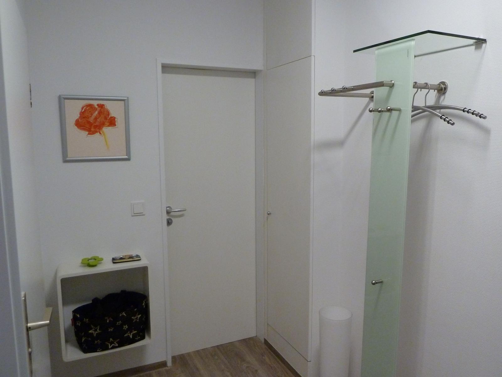 Flur mit Garderobe, Wandbild und kleinem Regal mit Tasche.
