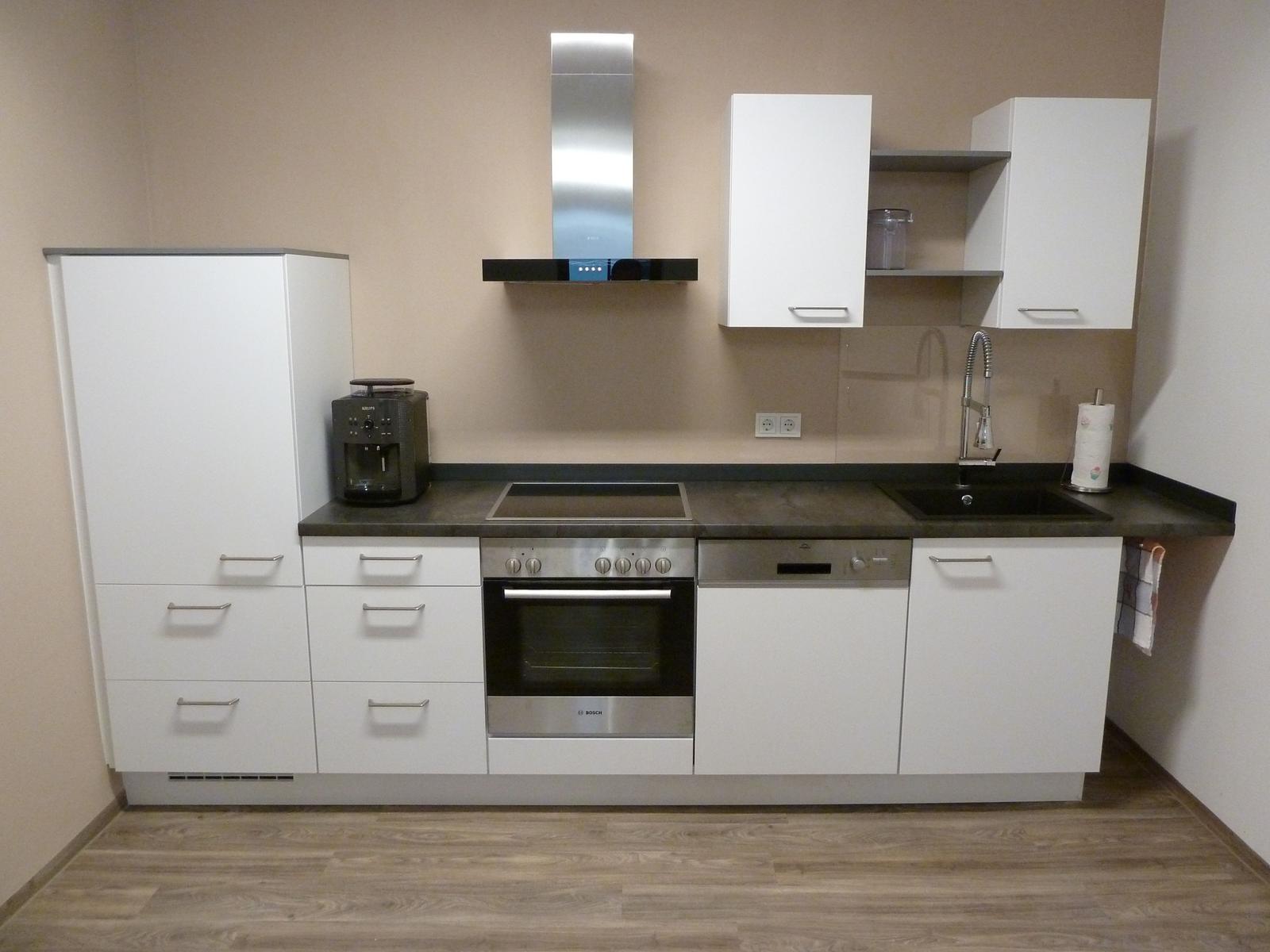 Moderne Küche mit weißen Schränken, Edelstahlspüle und Kochfeld.