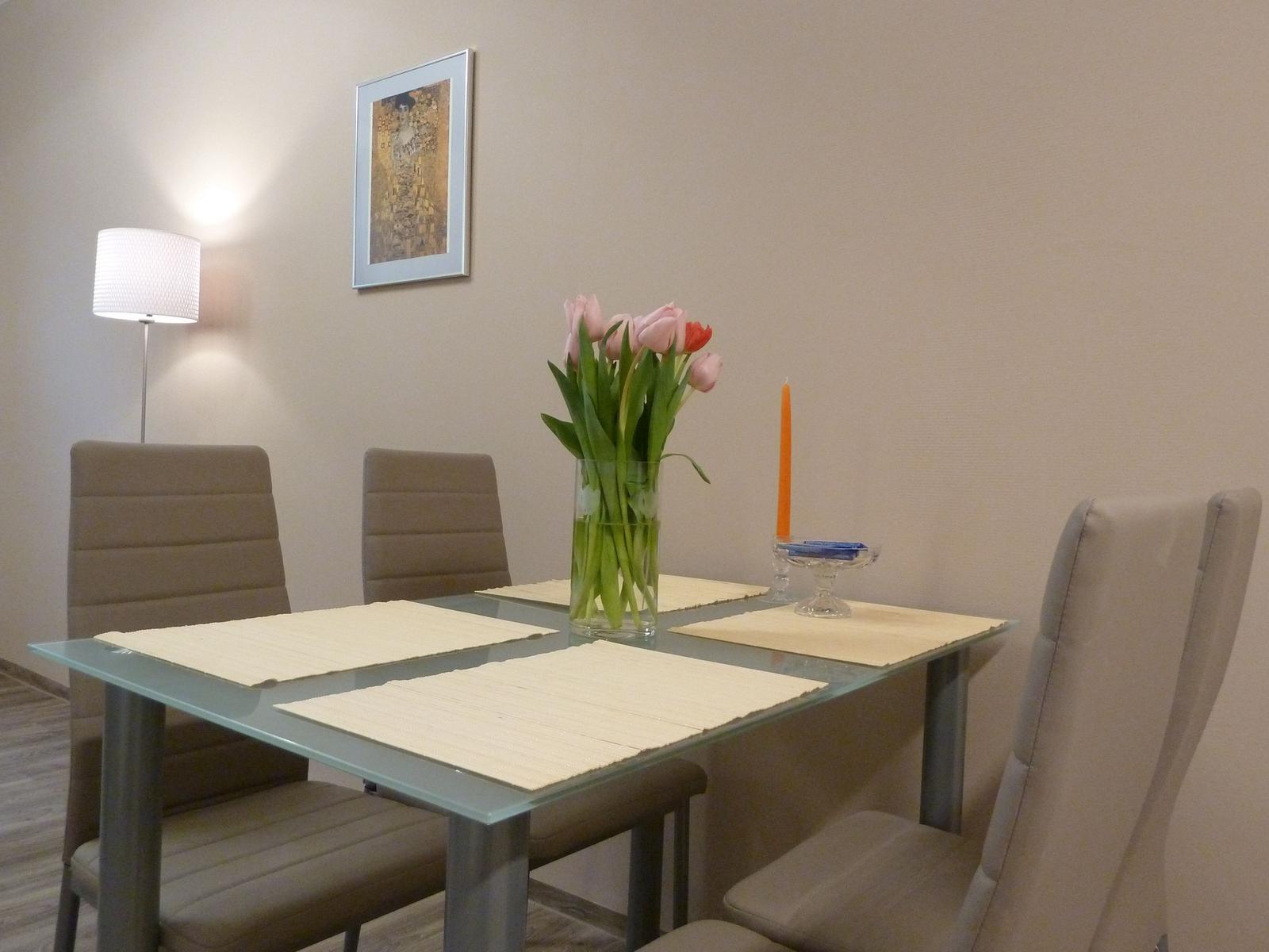 Esstisch mit vier Stühlen, Blumen und Kerze auf dem Tisch