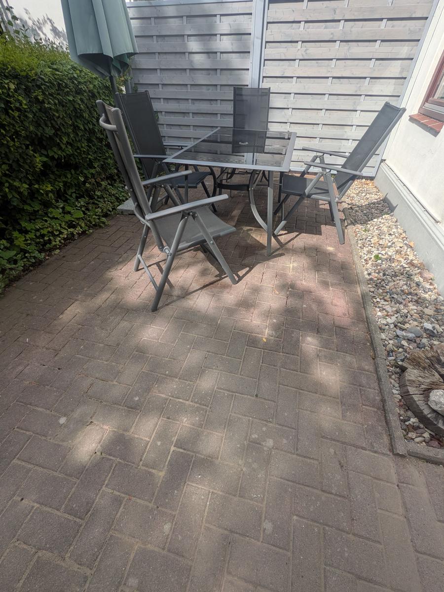 Terrasse mit Gartentisch, vier Stühlen und Sonnenschutz