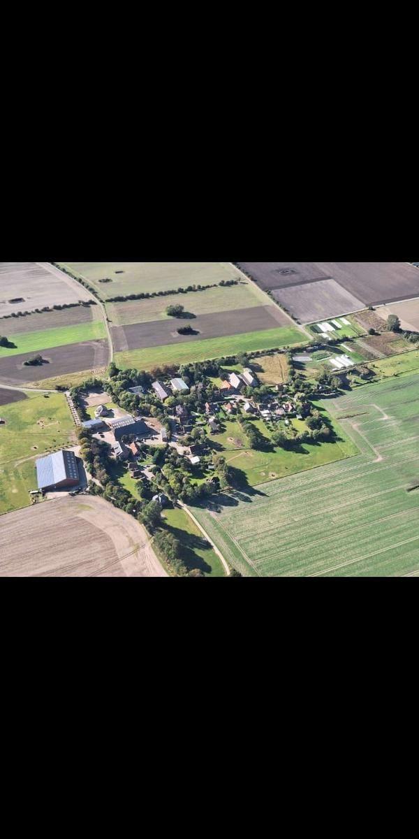 Aerielansicht eines ländlichen Dorfes mit Gebäuden und umliegenden Feldern.