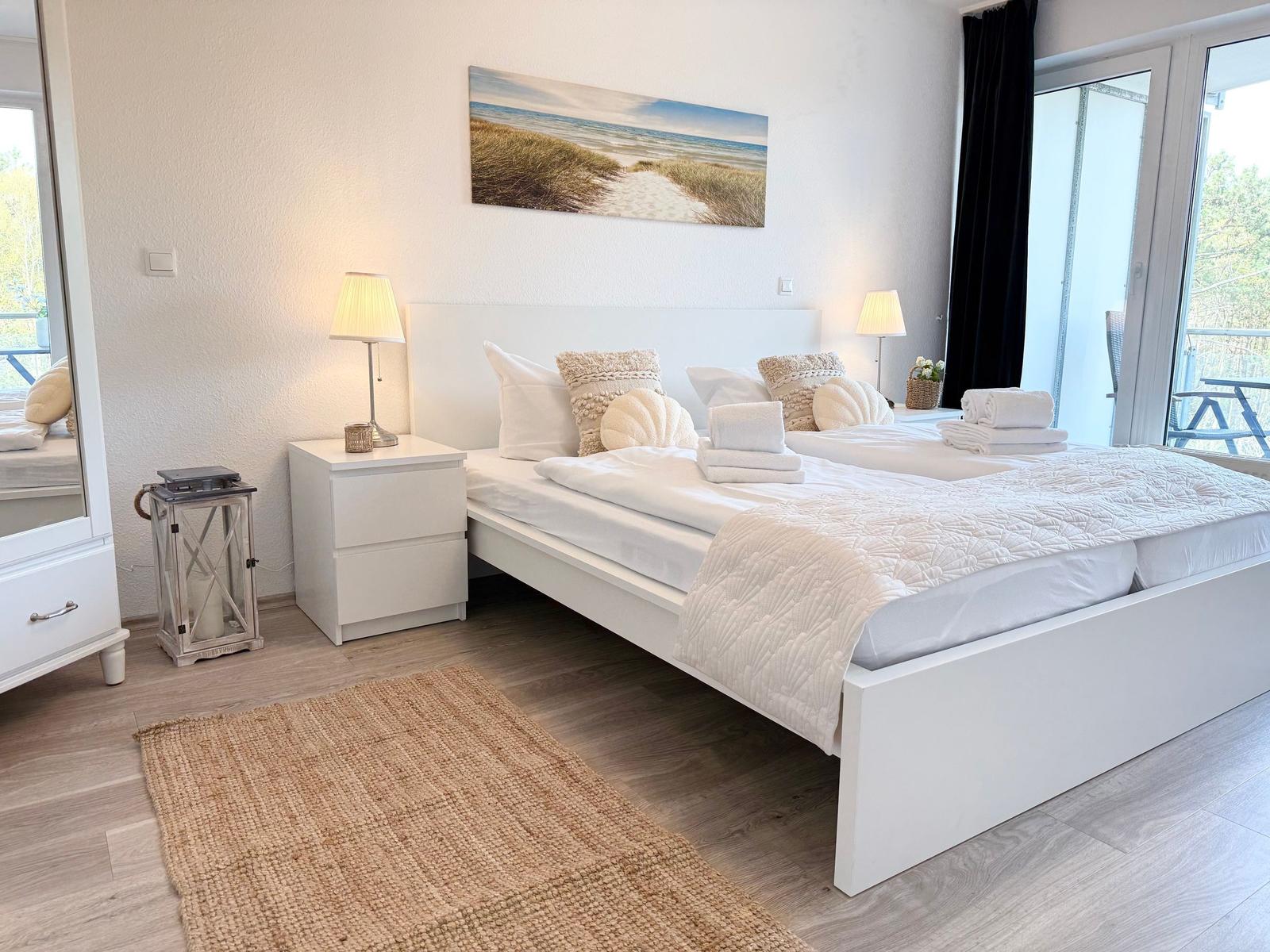 Schlafzimmer mit Doppelbett, Nachttischen und Balkonansicht.