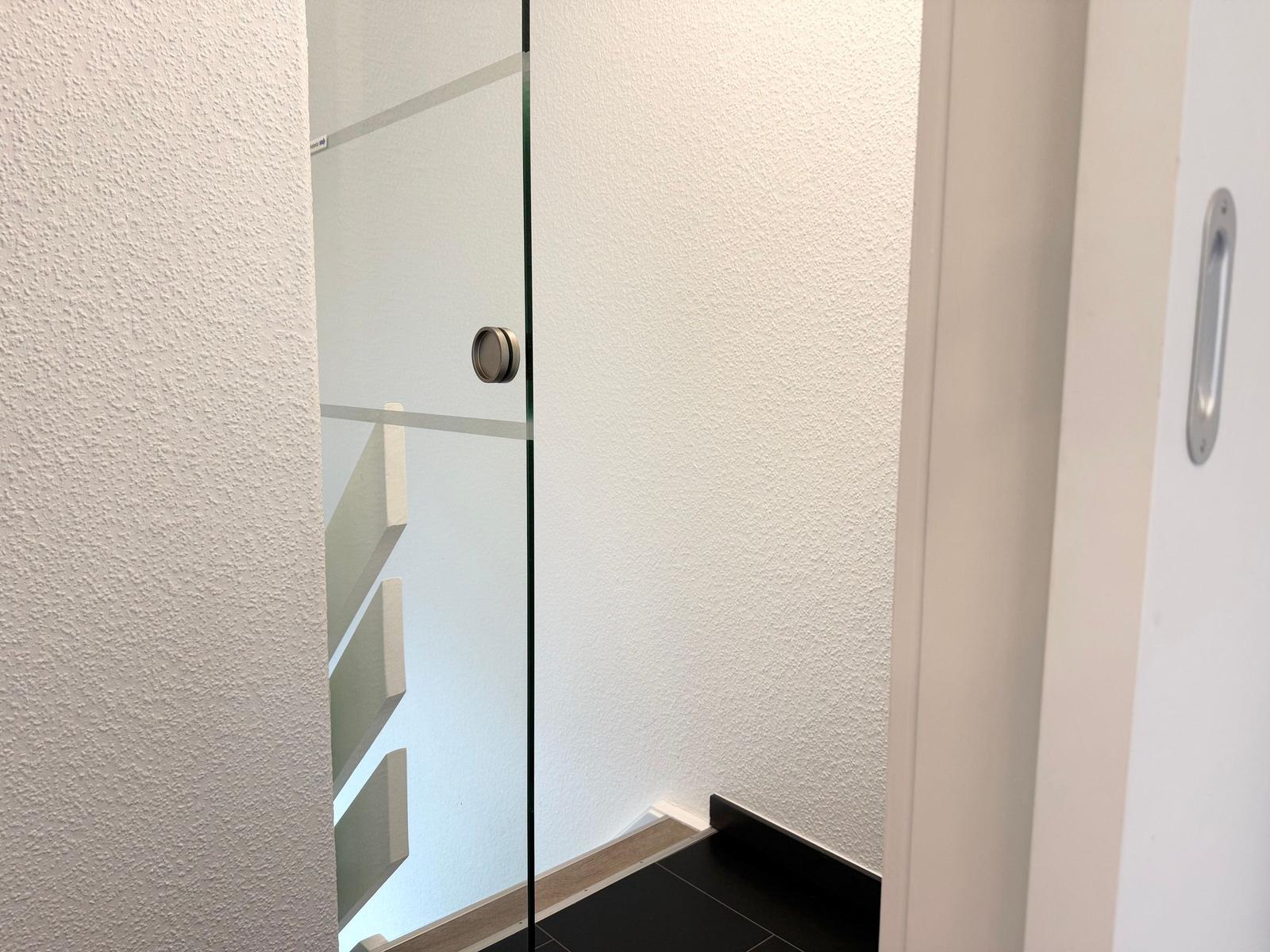 Glaswand mit Metallgriff und Stufen im Hintergrund