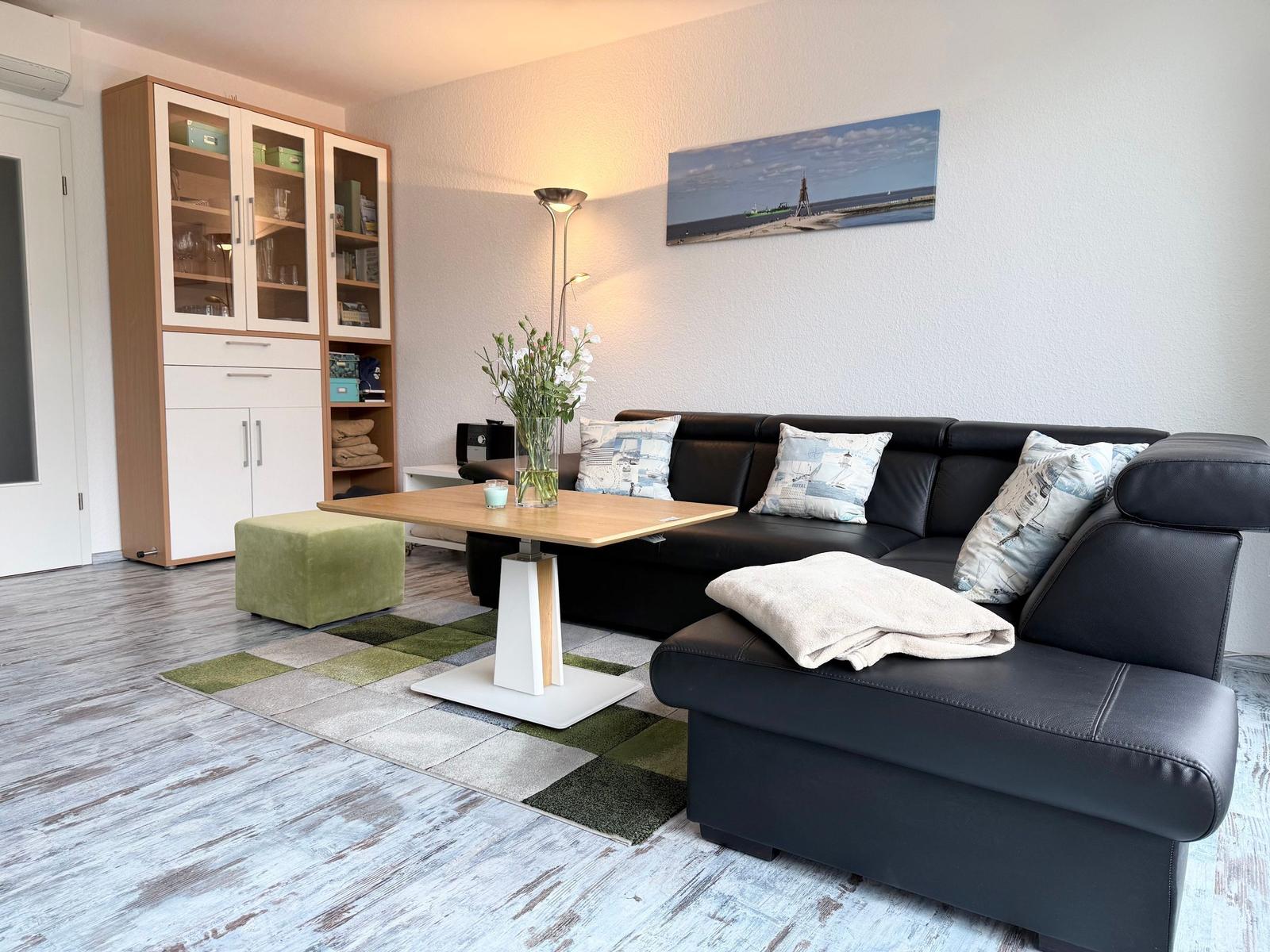 Ein Wohnzimmer mit einem schwarzen Sofa, einem Holztisch und einem Regal.