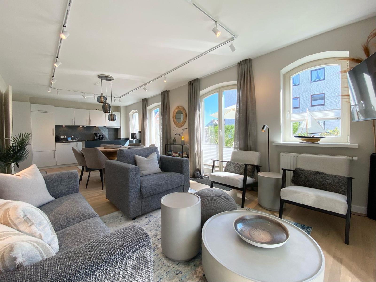 Wohnzimmer mit Sofa, Sitzgelegenheiten und Blick auf Balkon.