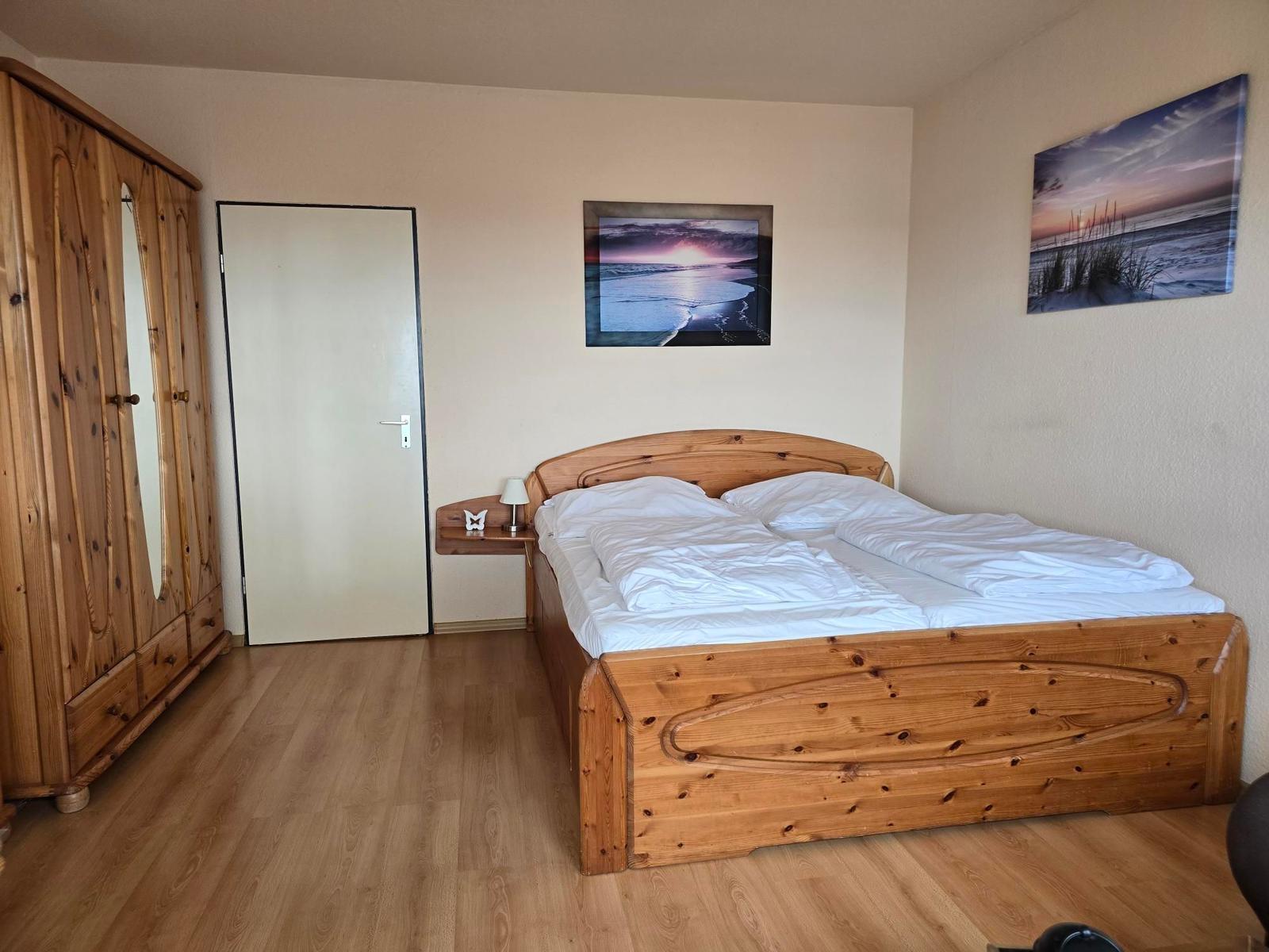Schlafzimmer mit Holzbett, Kleiderschrank und Wandbildern