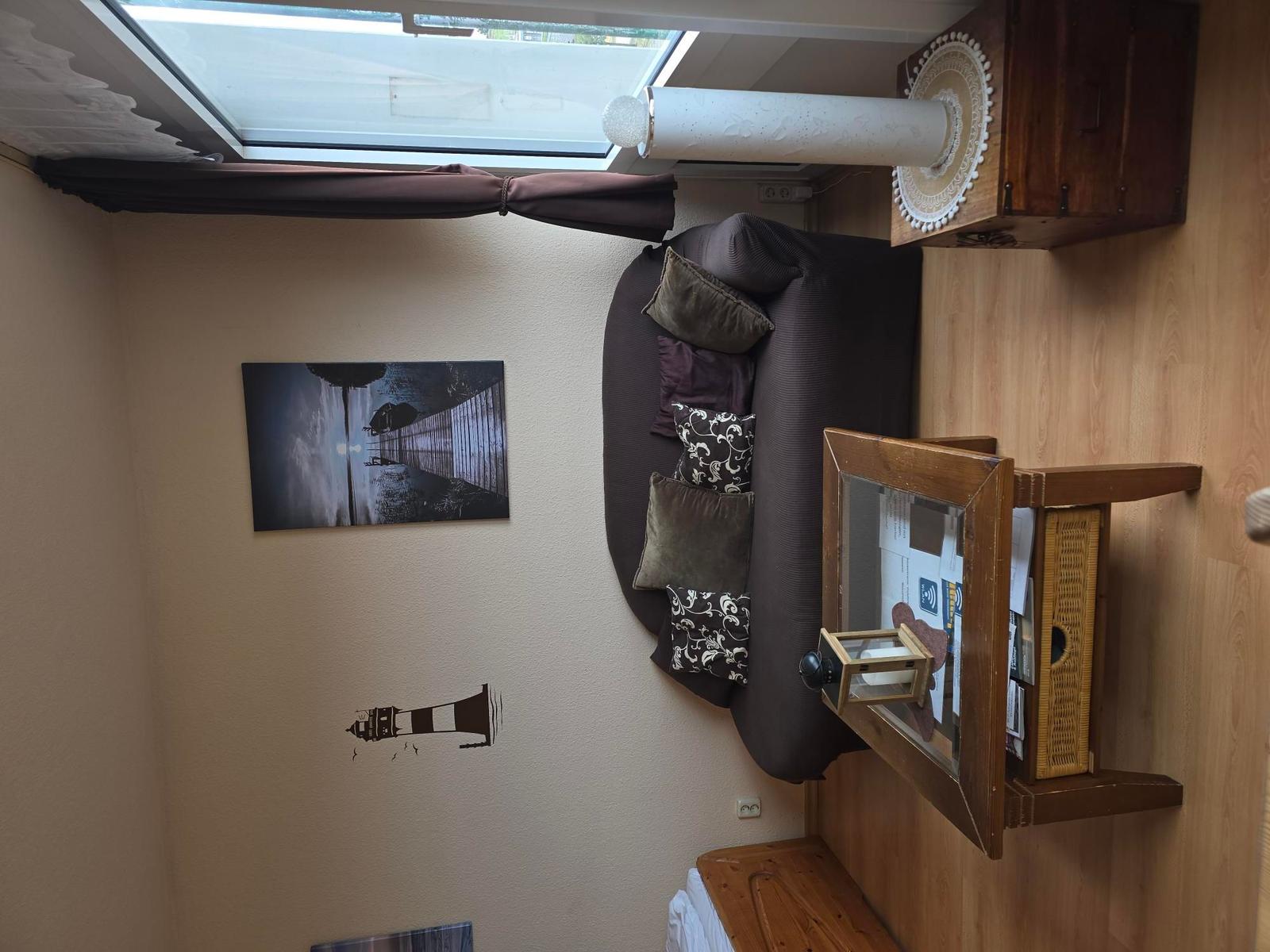 Zimmer mit Sofa, Wandbild und Dachfenster. Holzmöbel und Stehlampe.