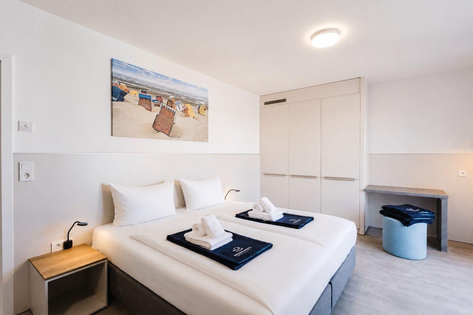 Schlafzimmer mit Doppelbett, Kleiderschrank und Wandbild mit Strandmotiv.