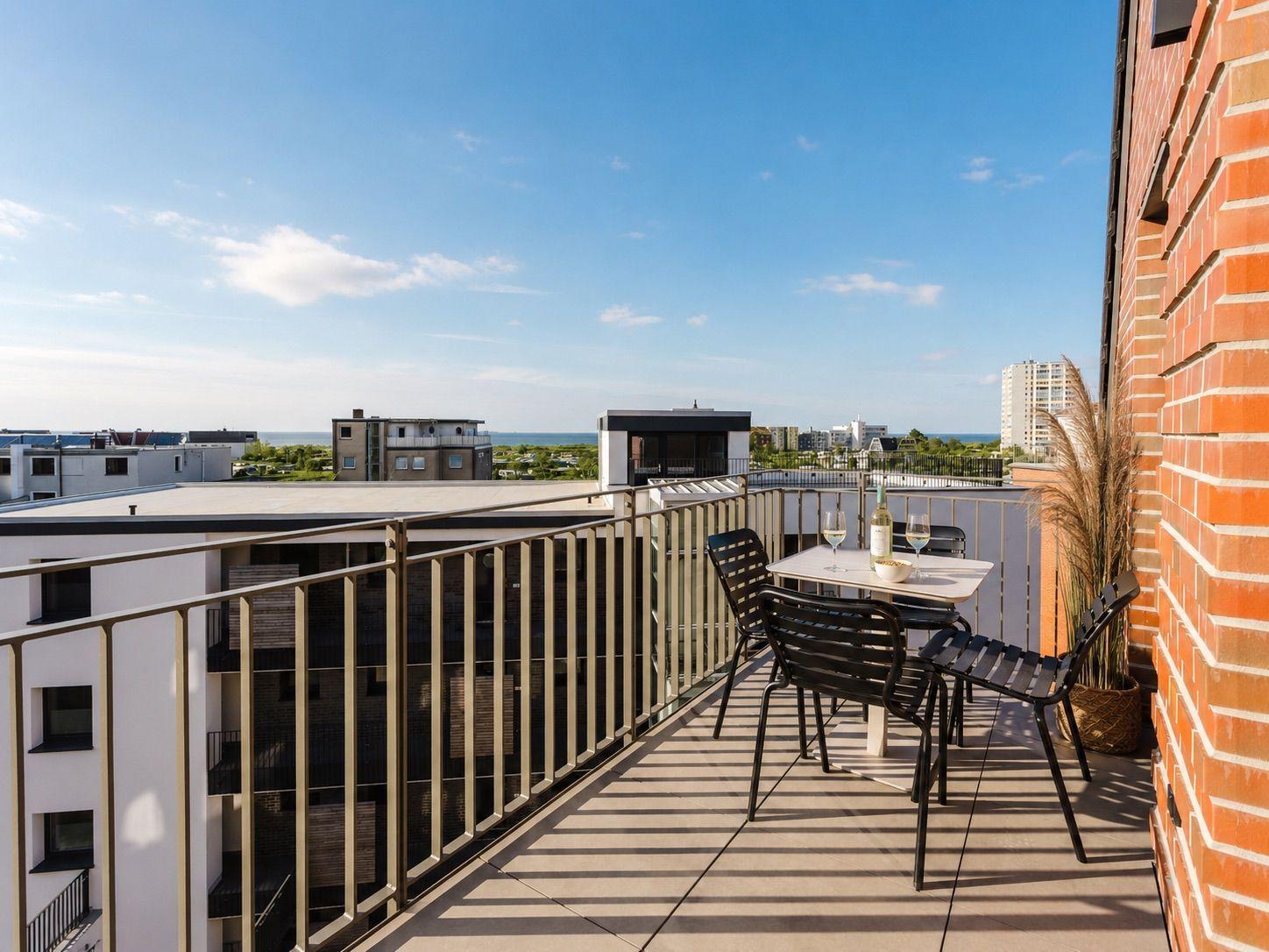 Terrasse mit Tisch und Stühlen, Blick auf Stadt und Meer.