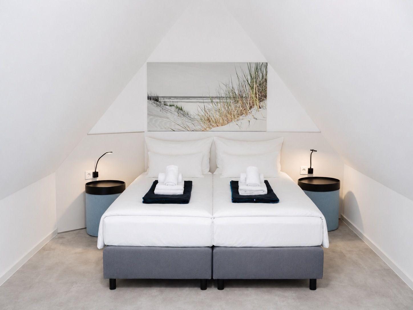 Schlafzimmer mit Doppelbett, zwei Nachttischen und Wandbild