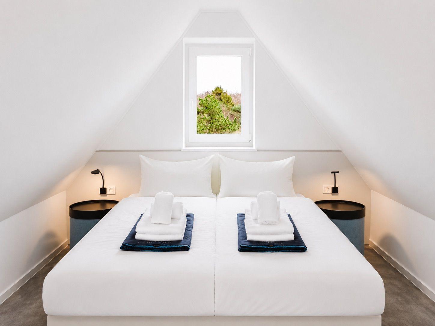 Schlafzimmer mit Doppelbett, Fenster und Nachttischen.