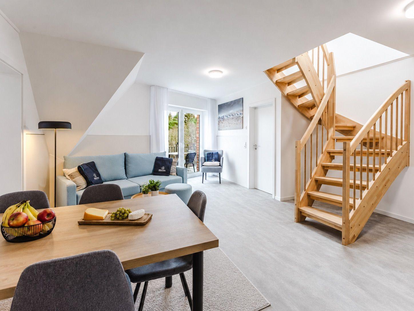 Wohn- und Essbereich mit Holztreppe und Sitzgelegenheiten.