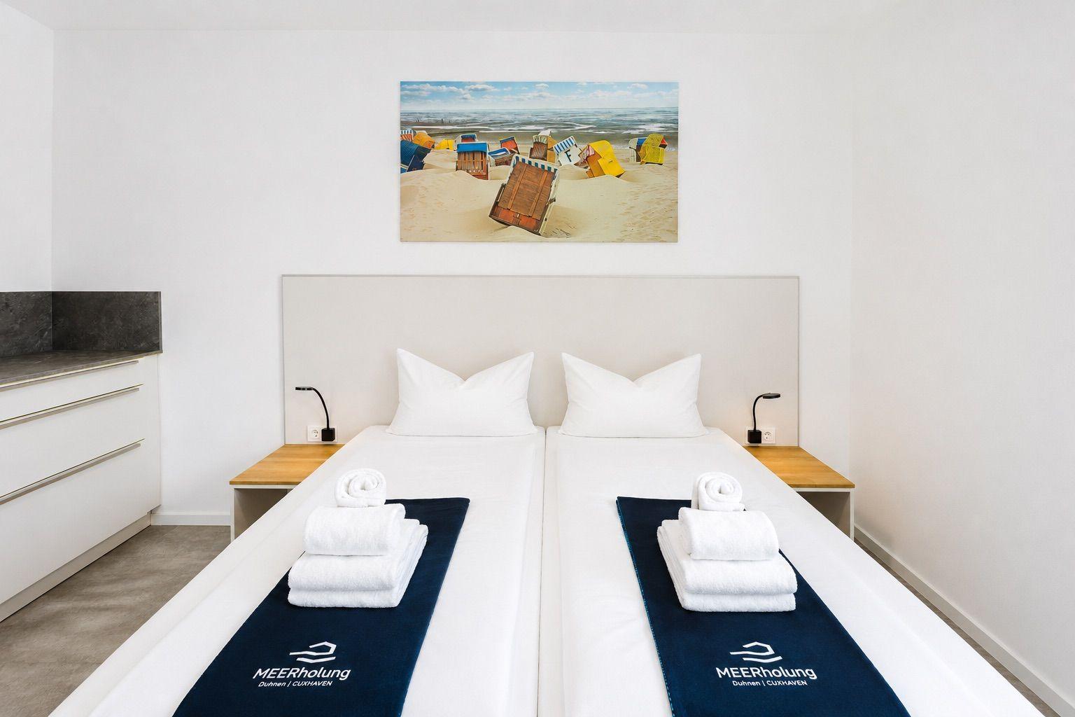 Zimmer mit Doppelbett, Wandbild und Badetüchern.