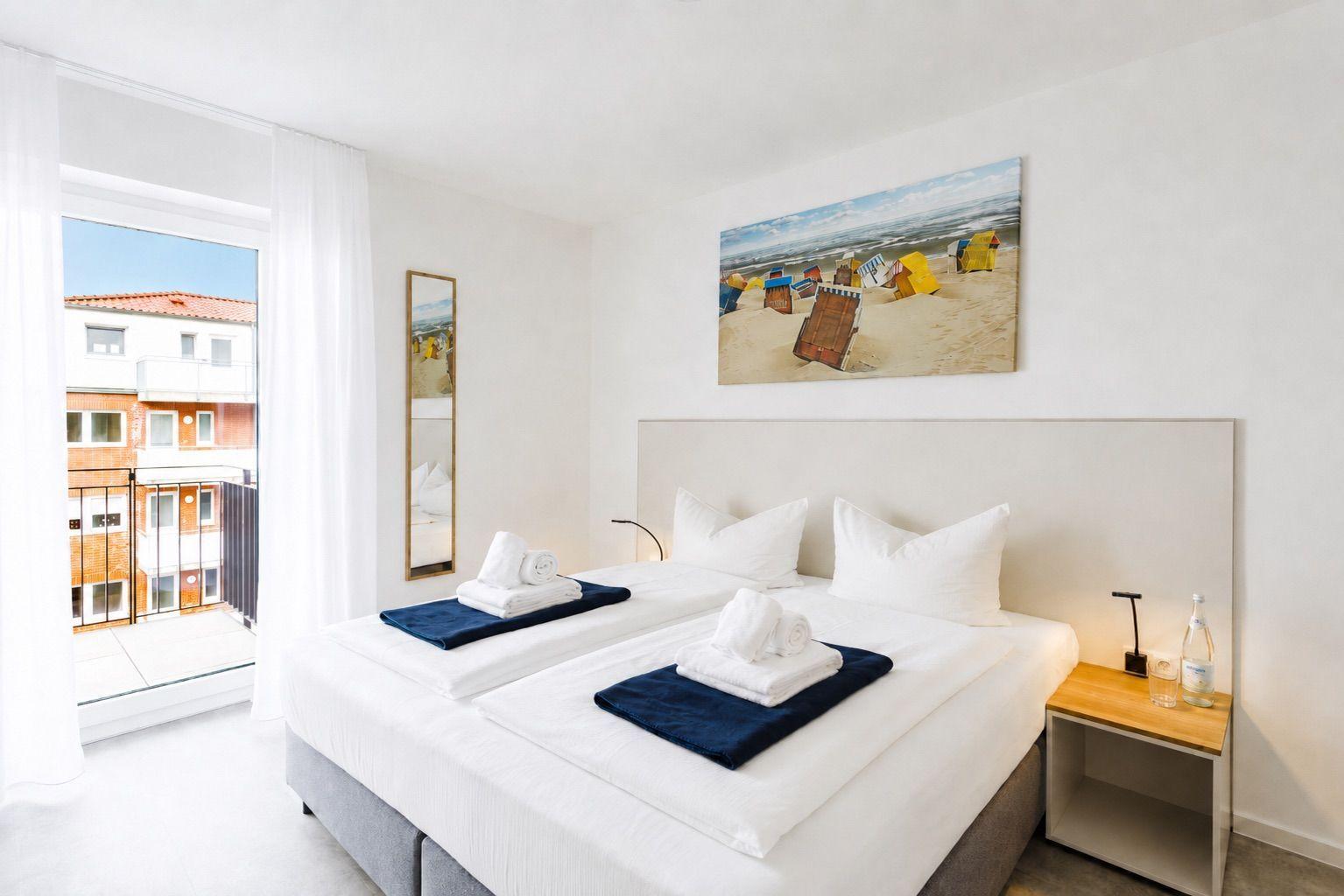 Schlafzimmer mit Doppelbett, Wandbild und Balkonansicht.