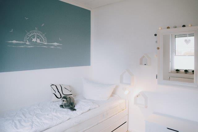 Bedroom with bed, wall art, and window view.
