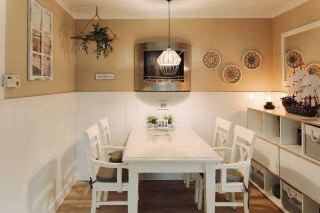 Dining area with white table, chairs, and ceiling fan. Wall decor and wooden floor.