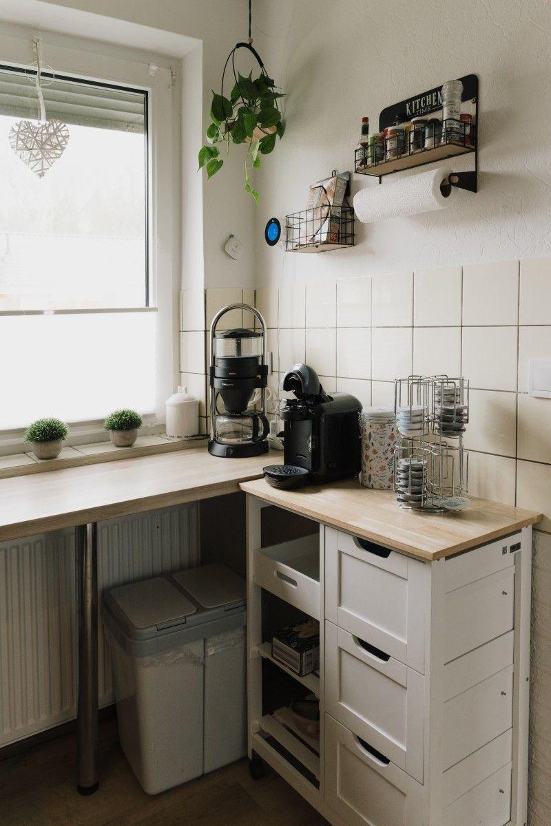Kitchen area with work surface, coffee machine, and plants by window.