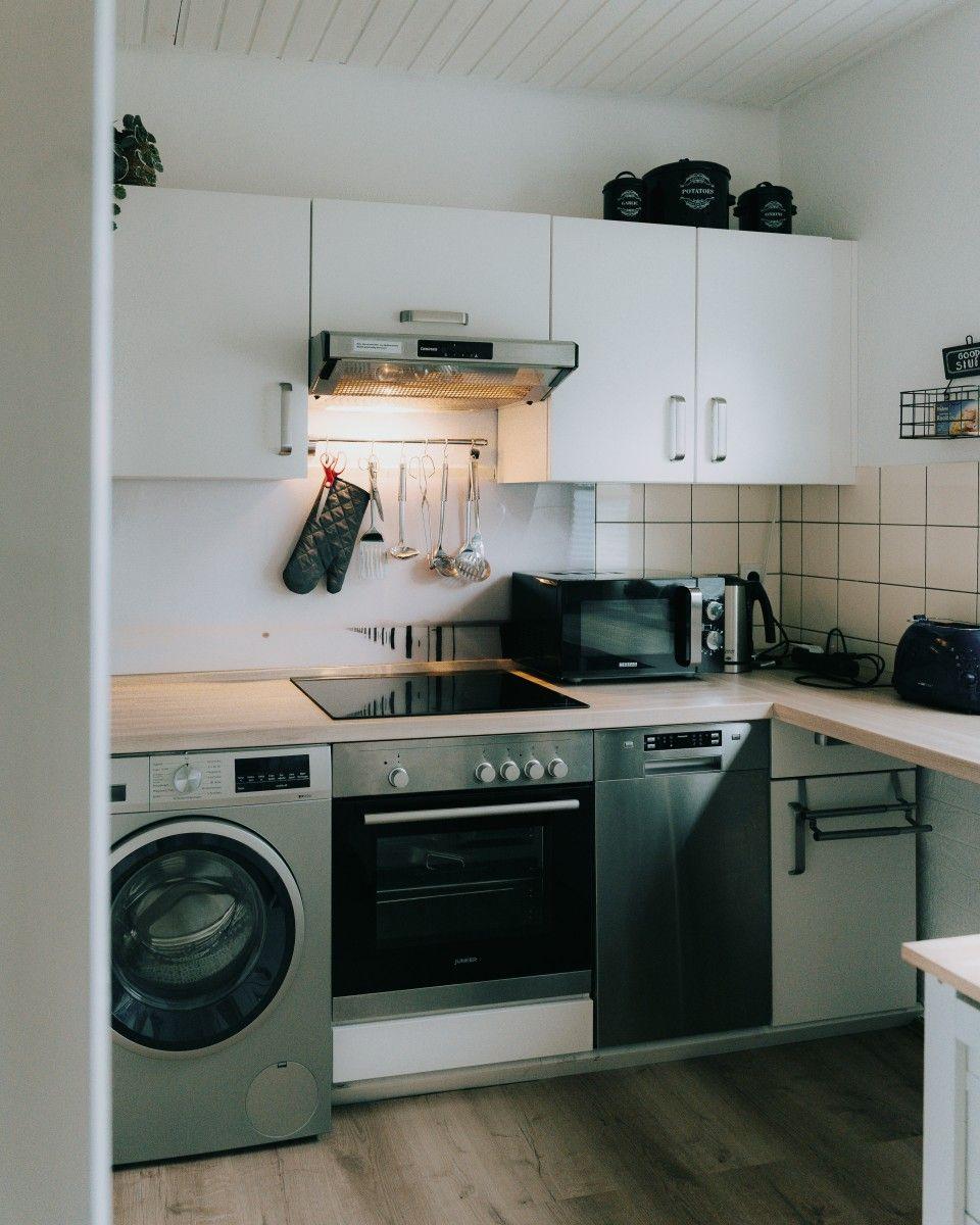 Kitchen with white cabinets, stainless steel appliances, and wooden tools on the wall.