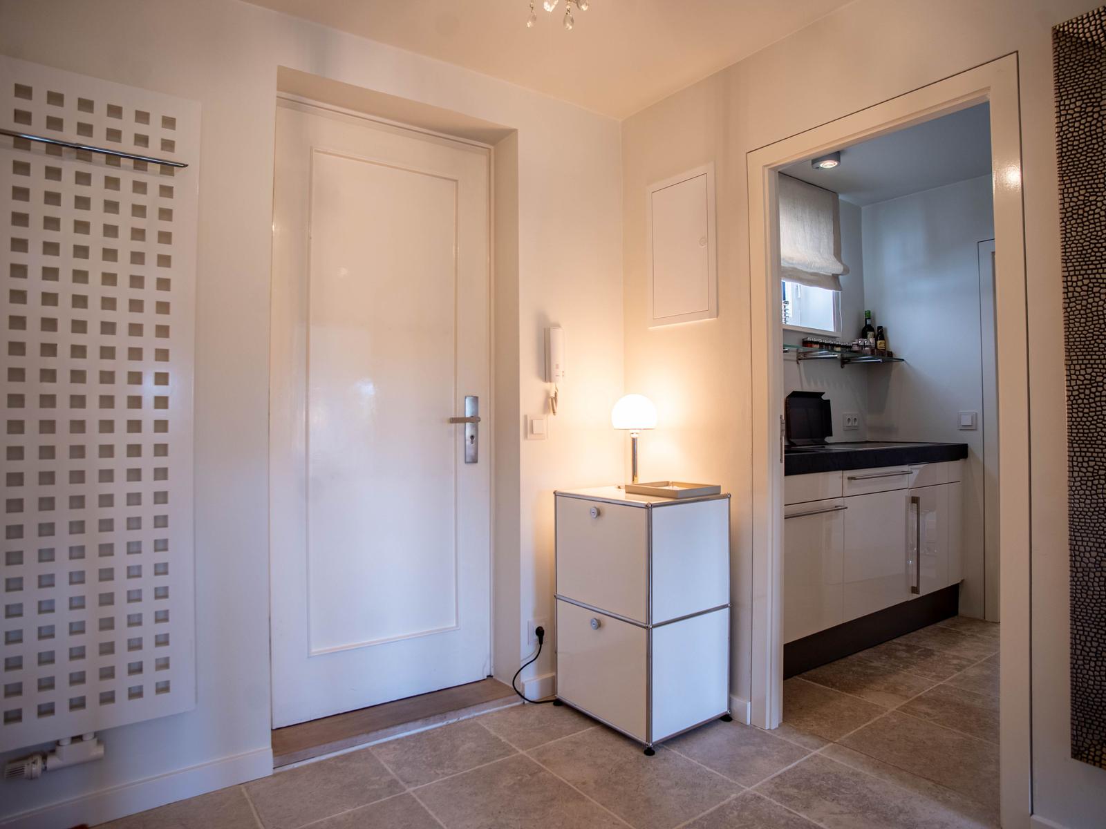 Eingangsbereich mit Tür, Schrank und Blick in die Küche.