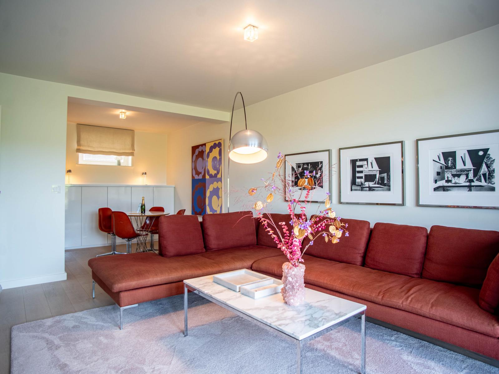 Ein Wohnzimmer mit rotem Sofa, marmerartigem Tisch und Wandbildern.