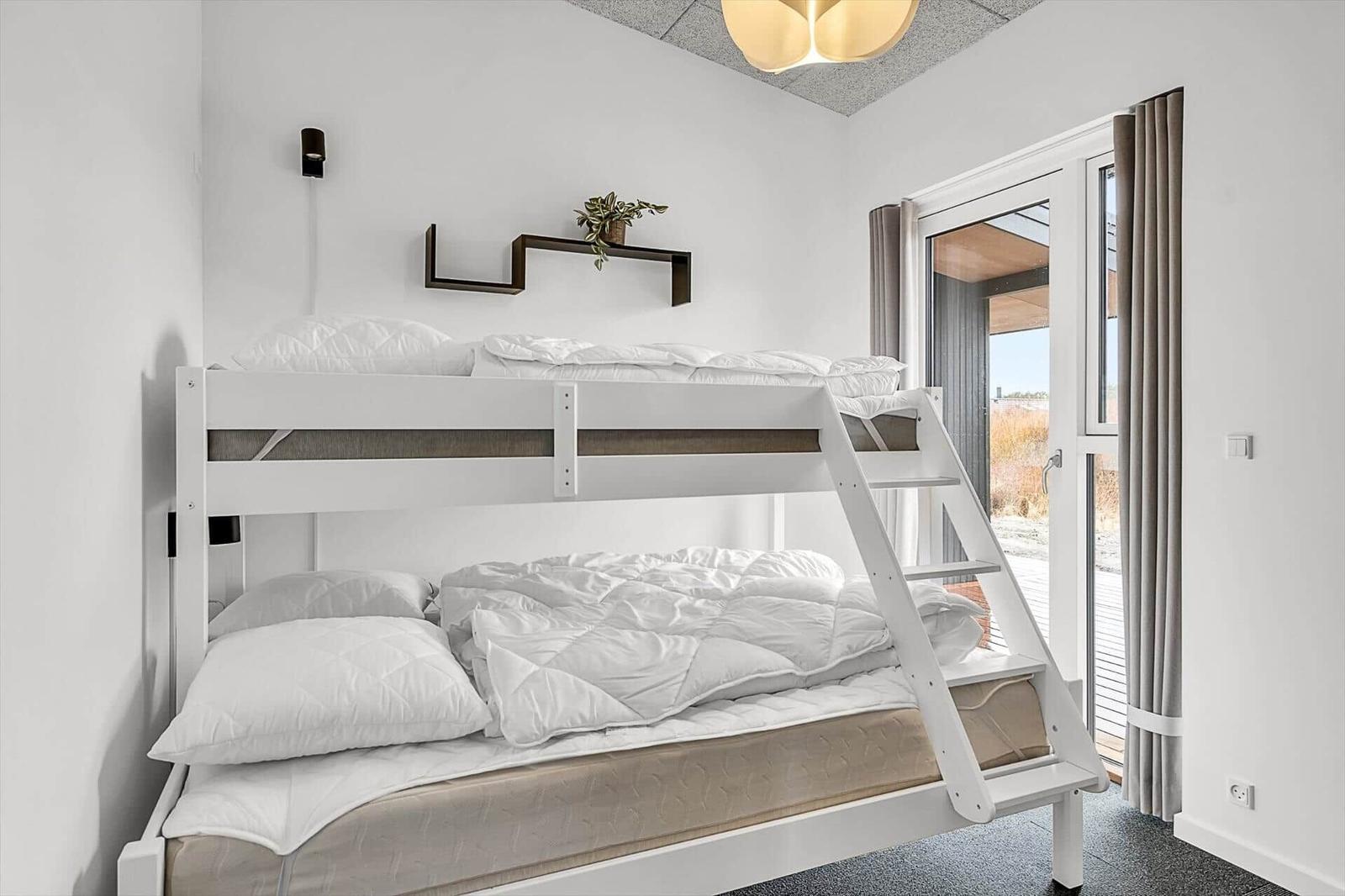 Ein Schlafzimmer mit einem Doppelstockbett und einer Glastür zum Balkon.