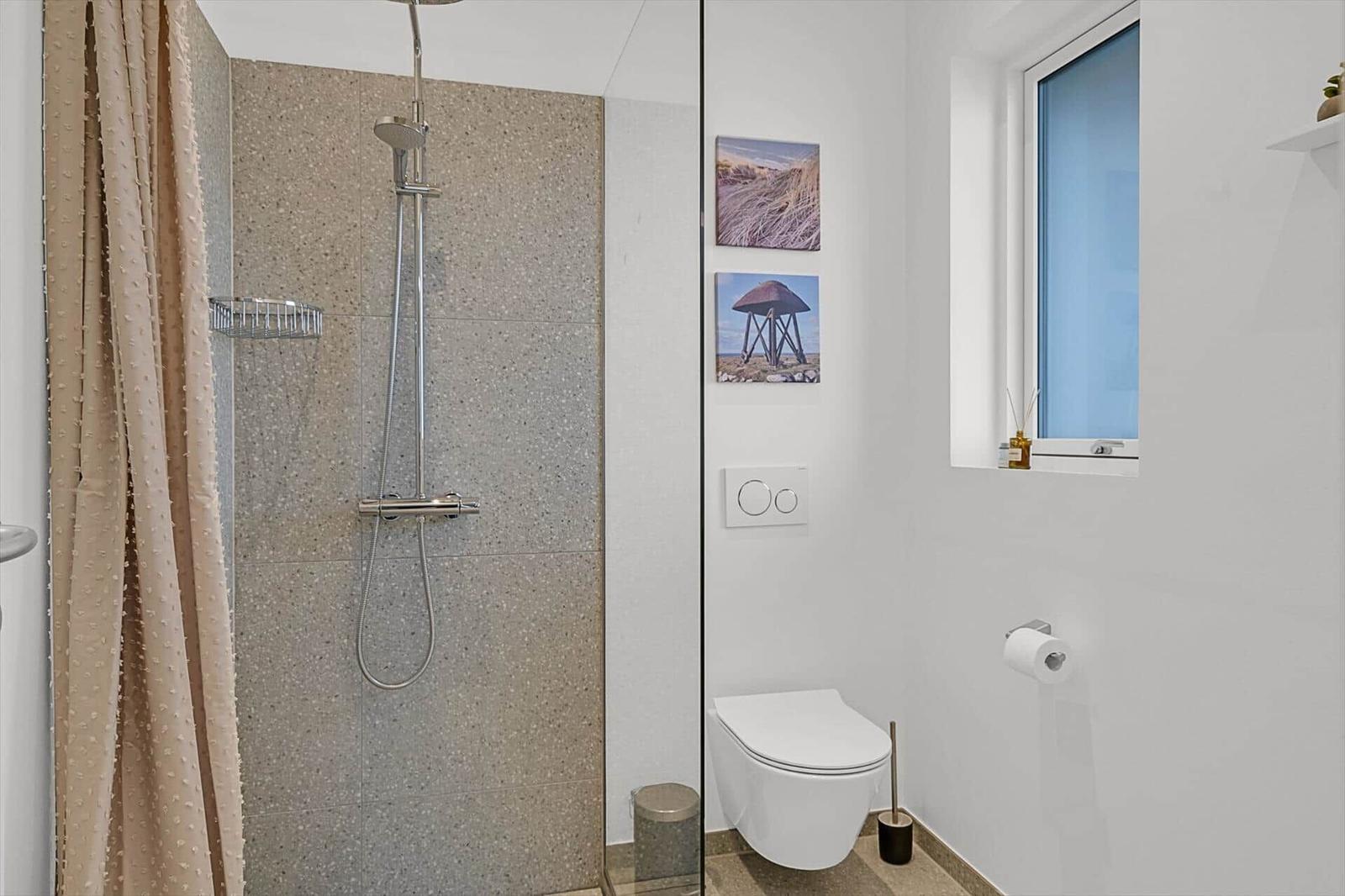 Badezimmer mit Dusche, Toilette und Fenster