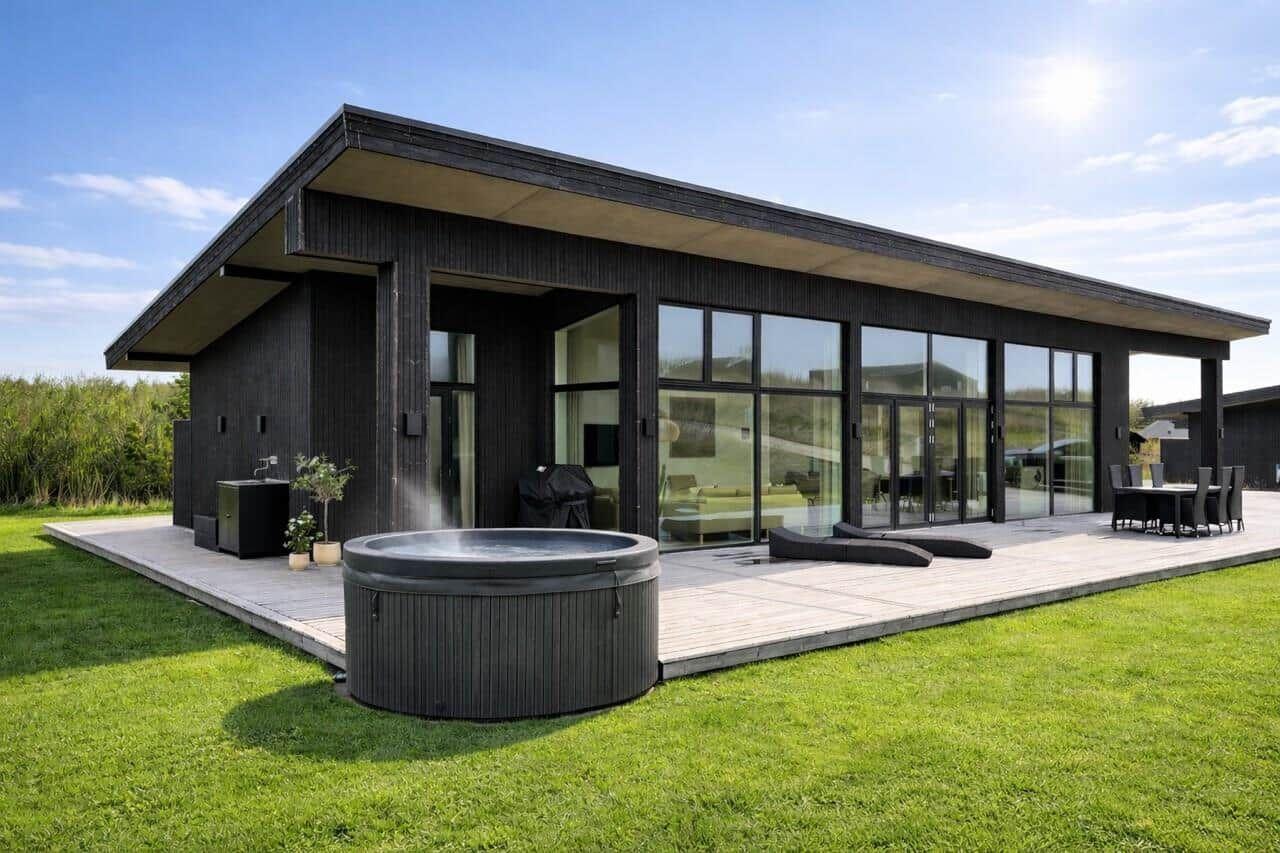 Moderne Villa mit Whirlpool, Terrasse und großem Glasbereich. Grünfläche und klare Sicht.