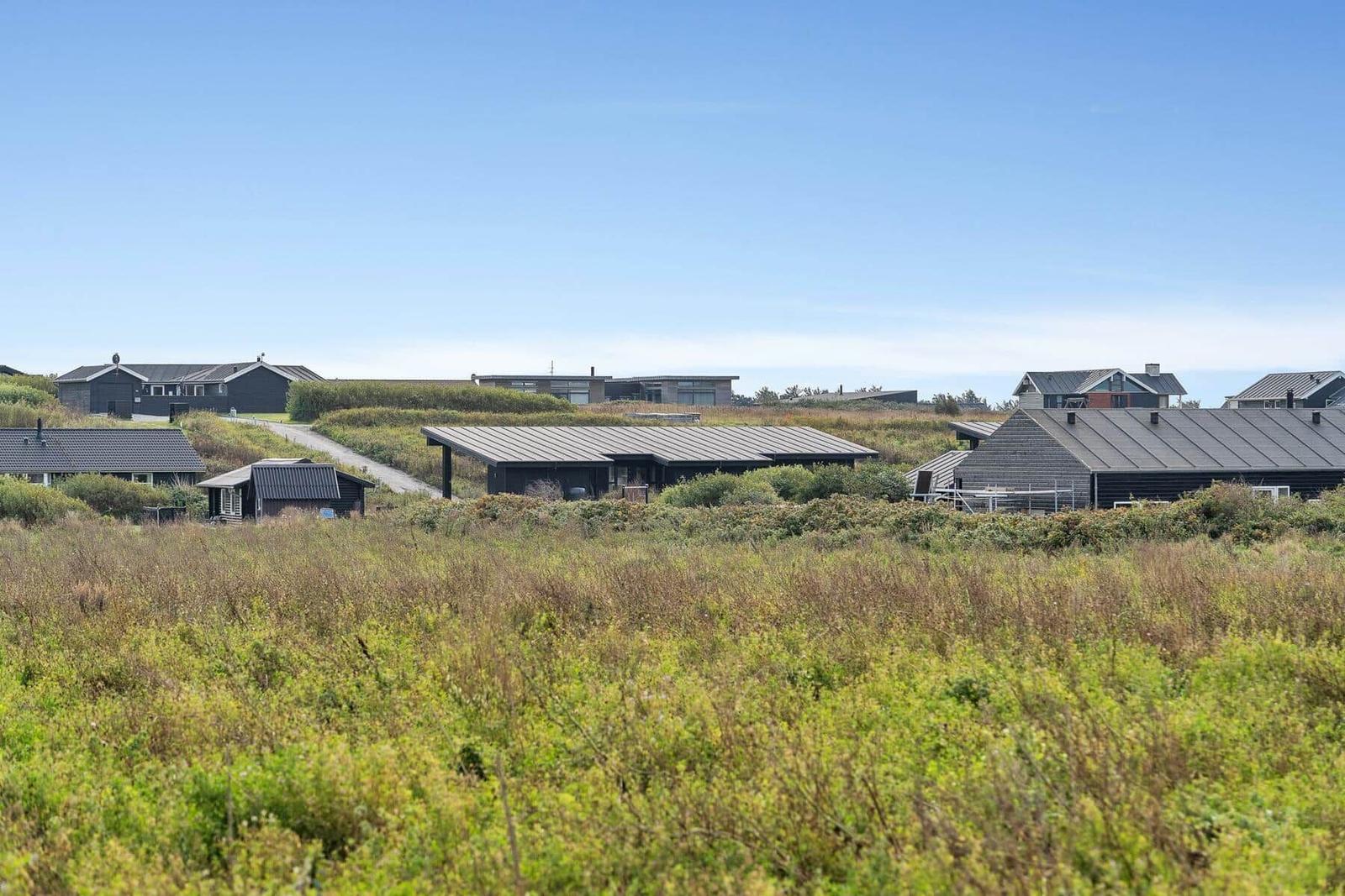 Moderne Häuser in einer grünen Landschaft unter blauem Himmel.