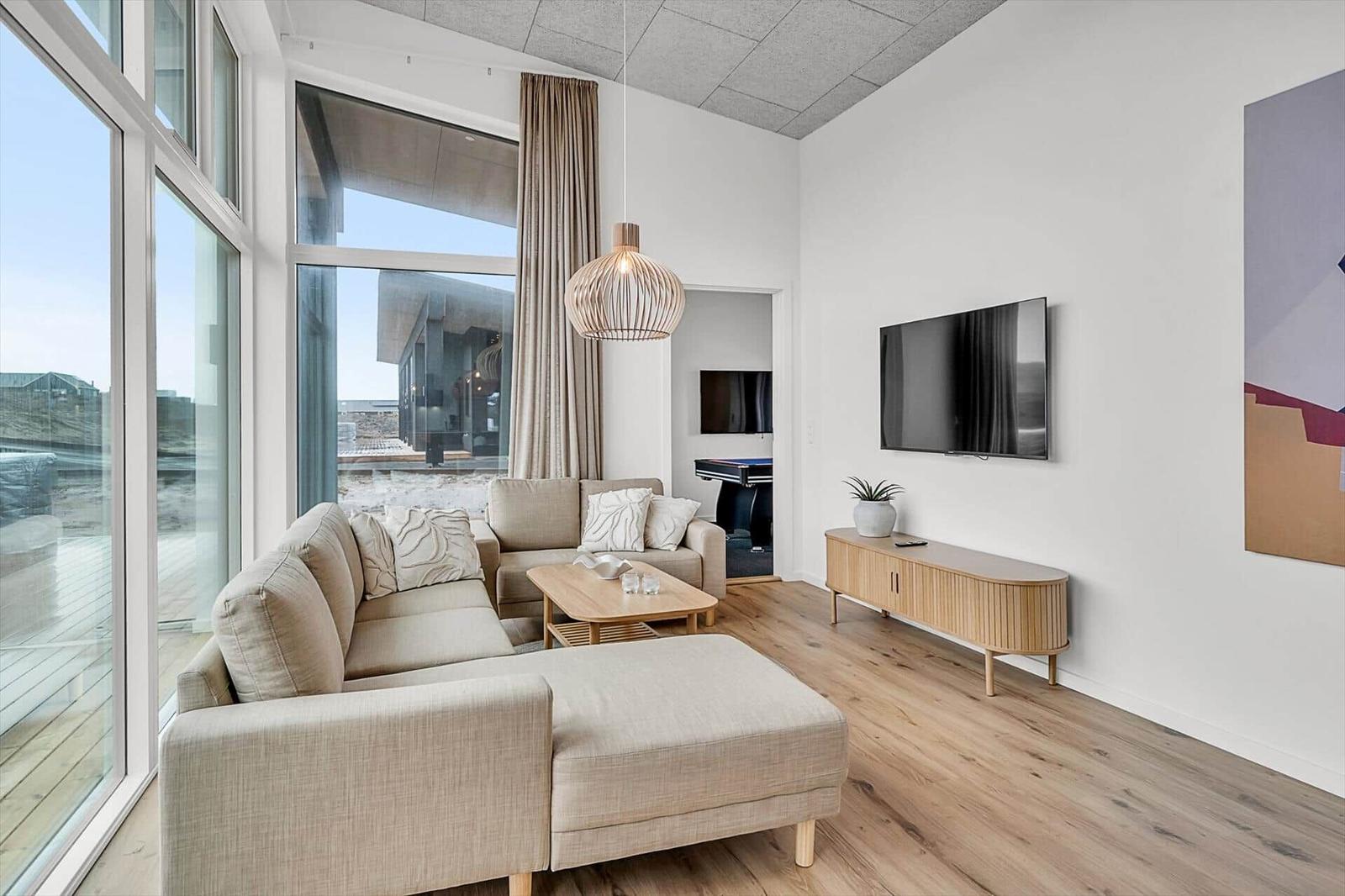 Wohnzimmer mit Sofa, Fernseher und großem Fensterblick.