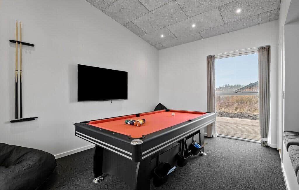 Raum mit Billardtisch, Fernseher und Blick auf die Außenterrasse.
