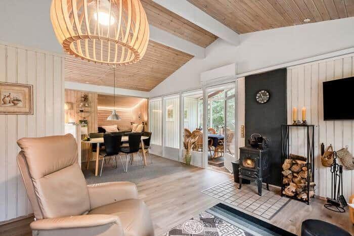 Wohnbereich mit Sitzgelegenheit, Esstisch und Kamin. Holzdecke und Terrassentür.