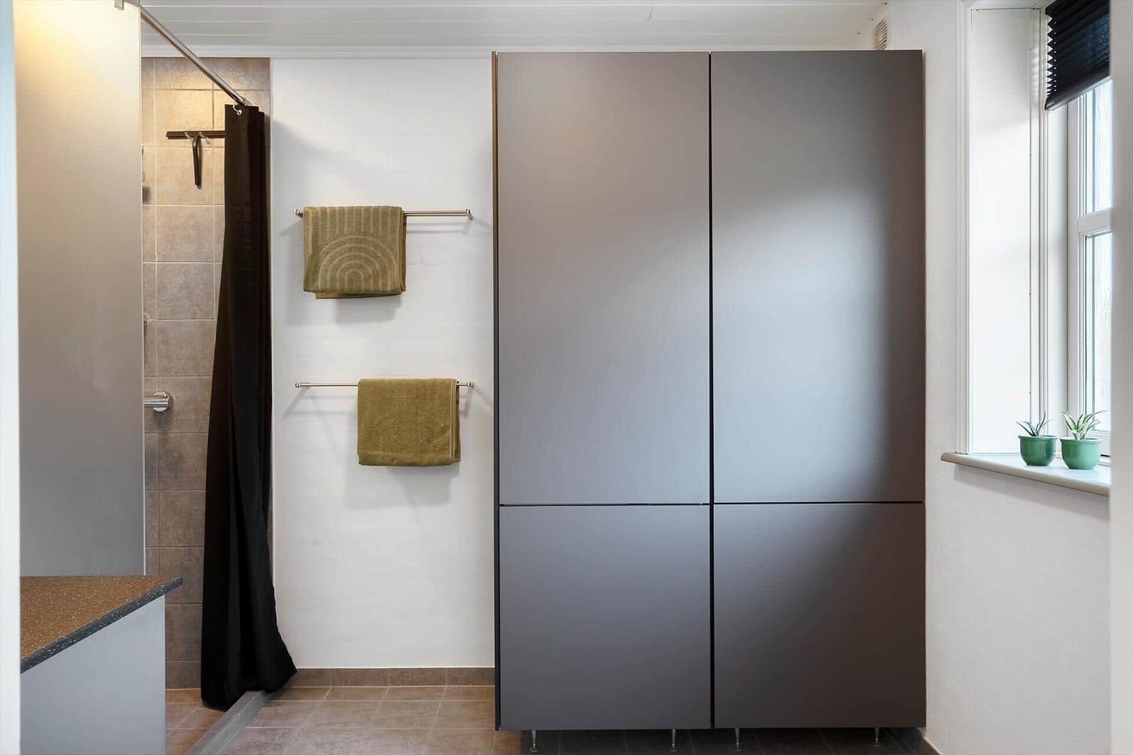 Badezimmer mit Dusche, Badewanne, Handtuchhaltern und Fenster mit Pflanzen.