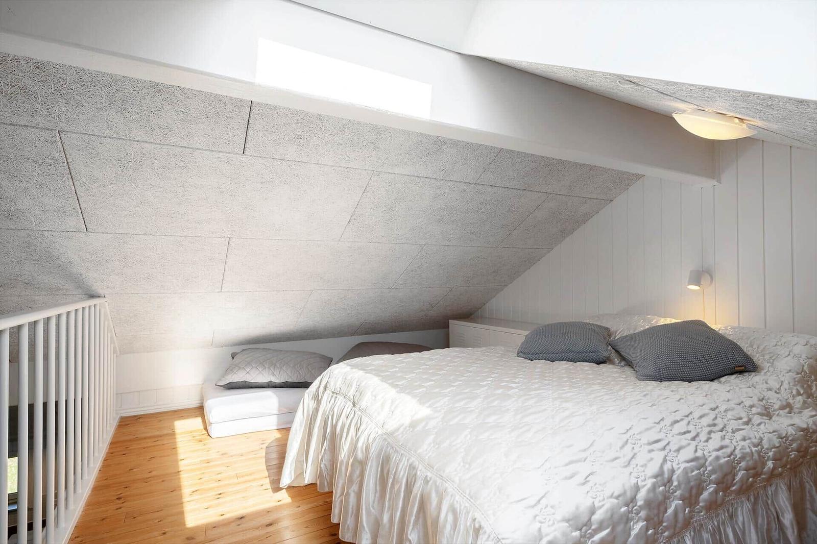 Schlafzimmer mit Dachschrägen, Bett und Sitzgelegenheit