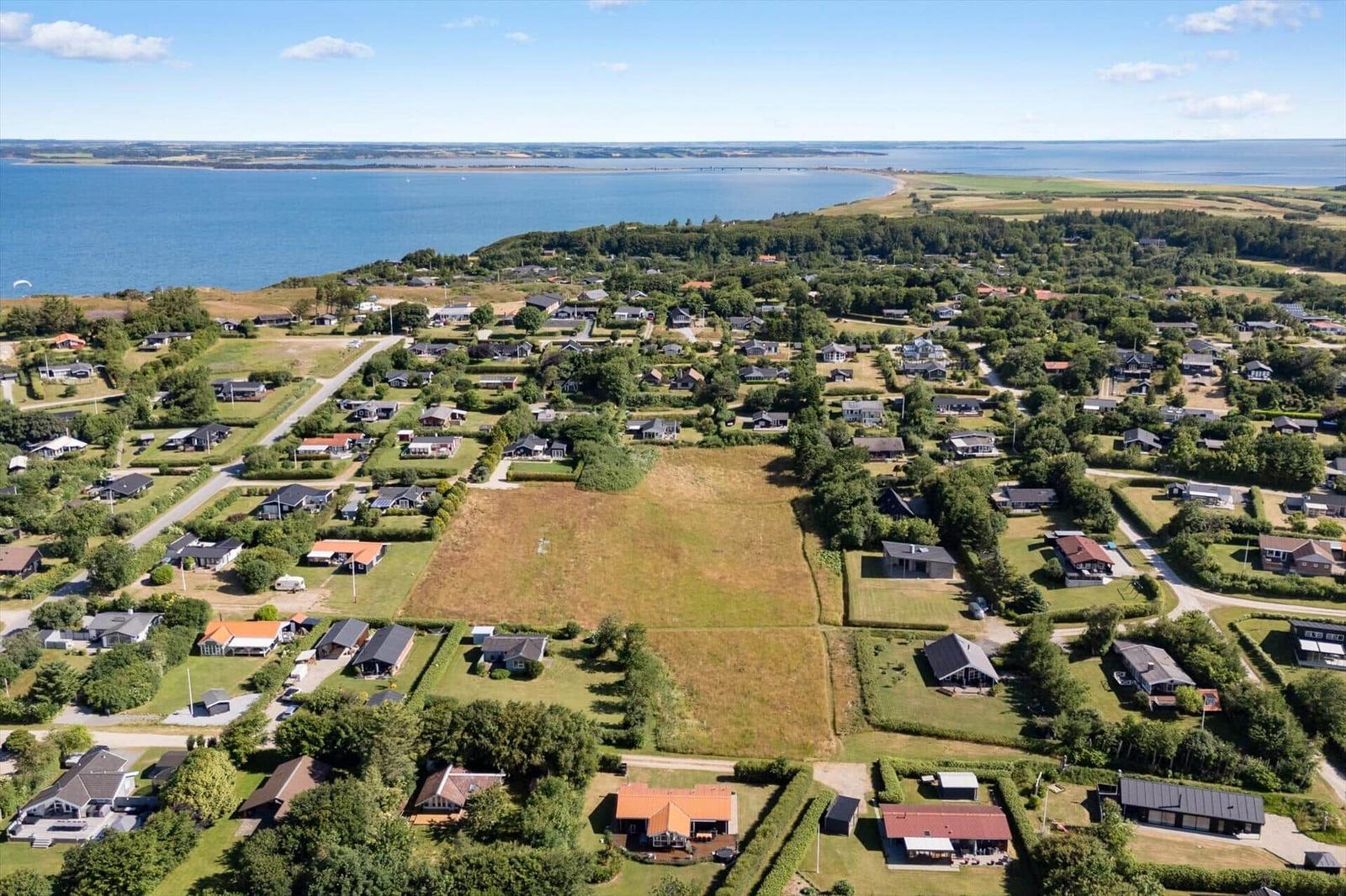 Luftbild von Ferienhäusern am Meer mit Grünflächen und Straßen.