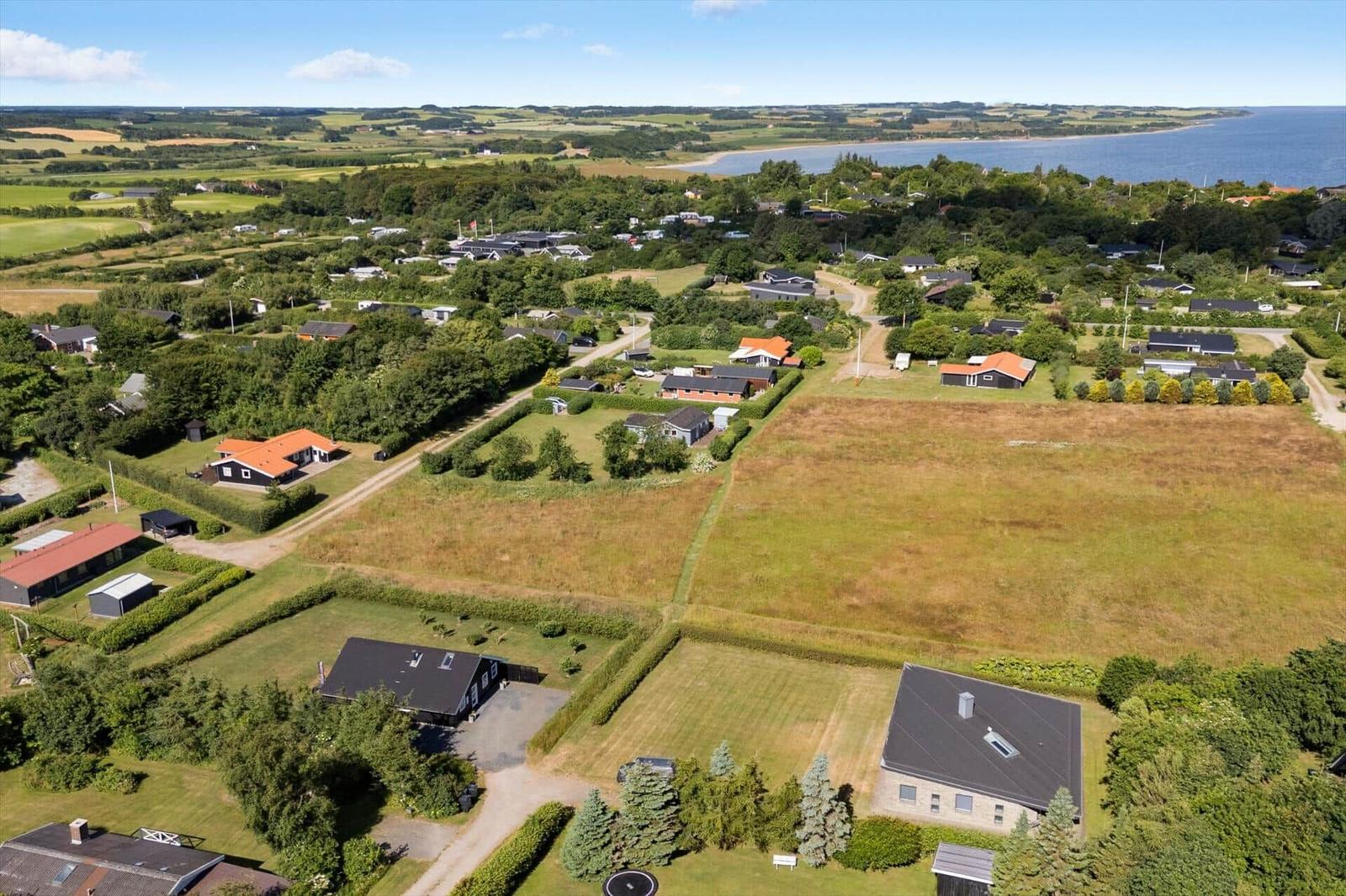 Luftbild einer Wohngegend mit Häusern, Wiesen und Blick auf die Küste.