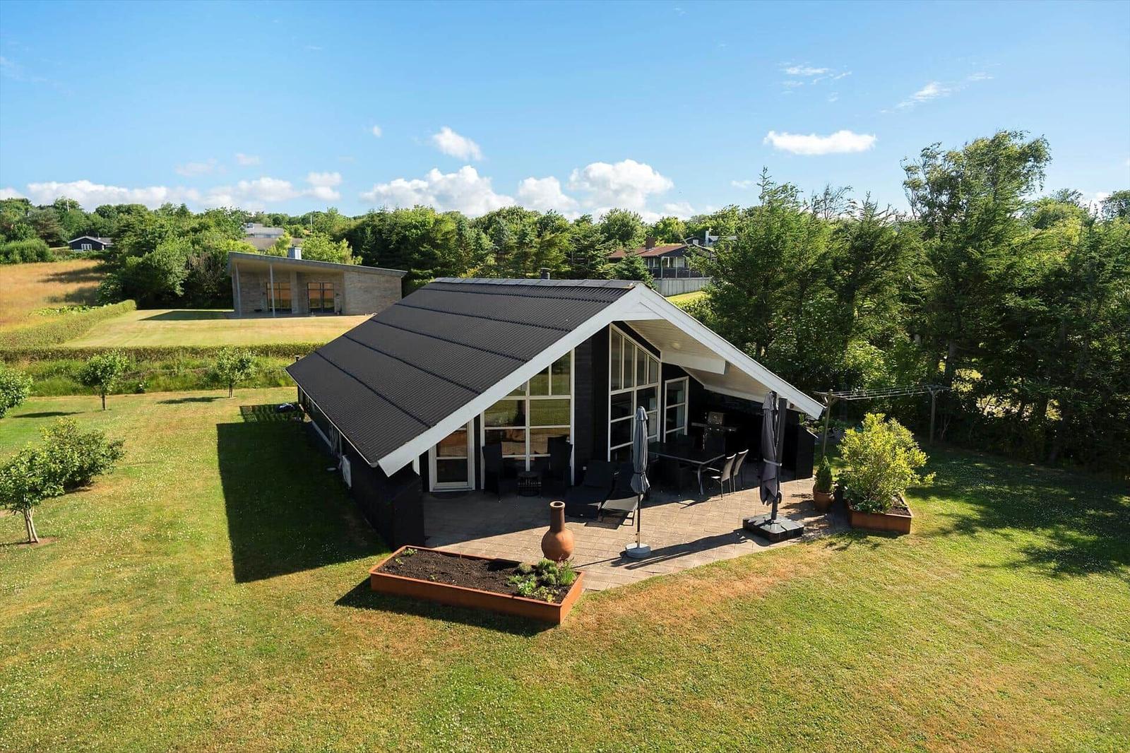 Moderne Villa mit Terrasse, Garten und Blick auf Wald.