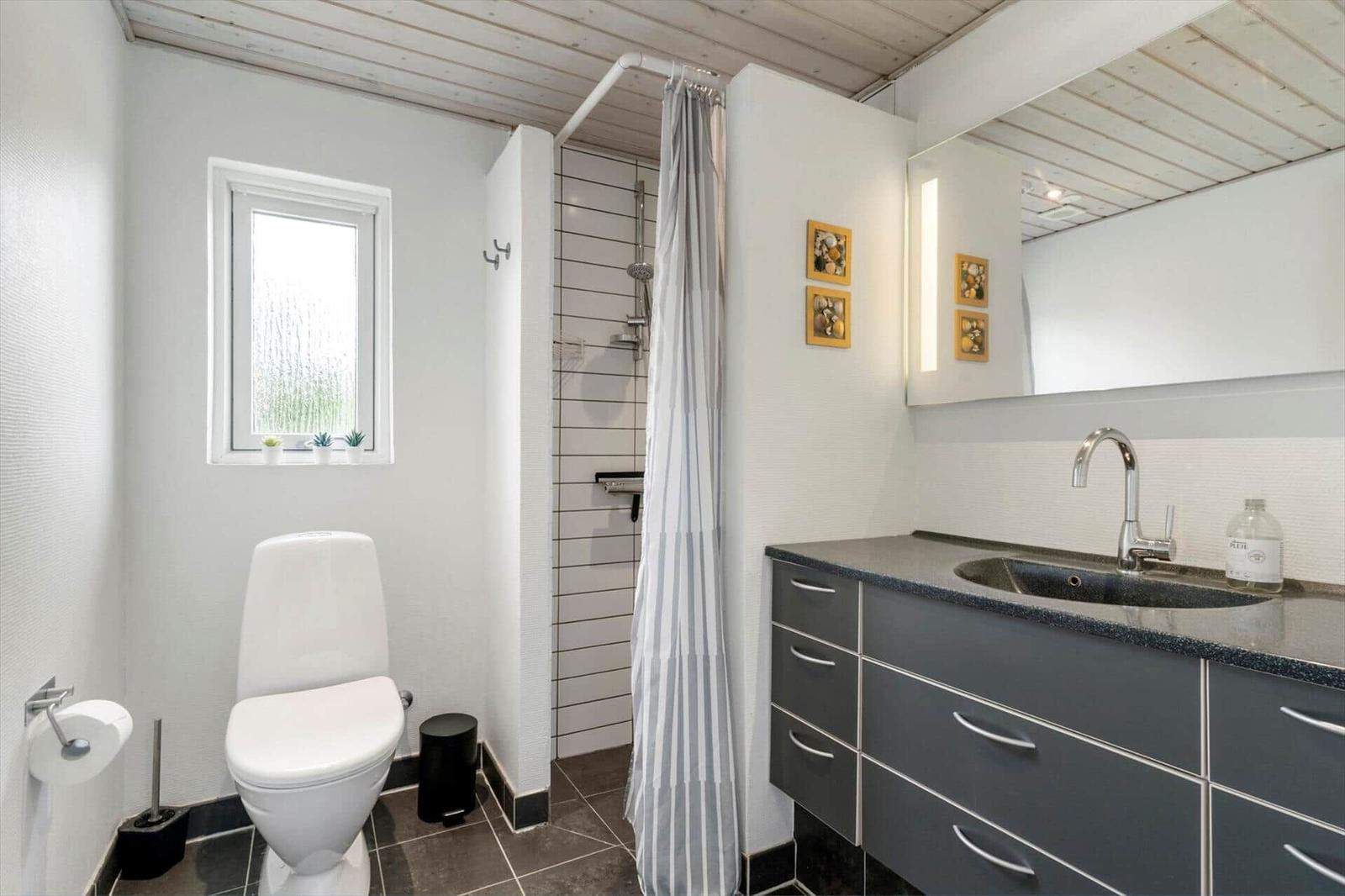Badezimmer mit Toilette, Dusche und Waschbecken mit Spiegel.